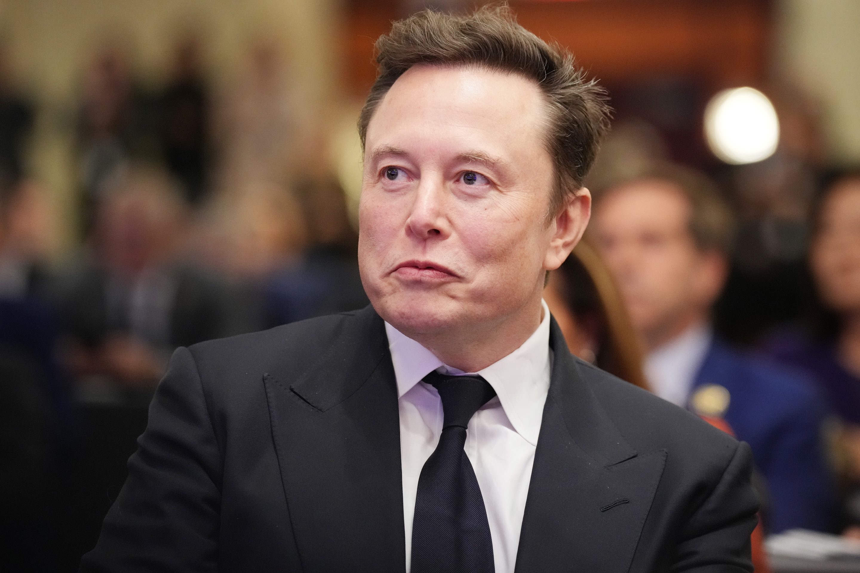 Elon Musk listens as U.S. President-elect Donald Trump addresses a House Republicans Conference meeting at the Hyatt Regency on Capitol Hill on November 13, 2024 in Washington, DC
