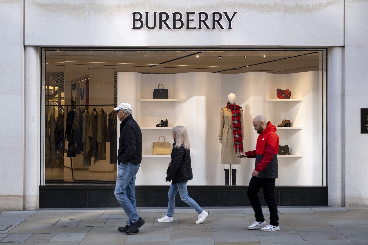 people walking past a burberry store