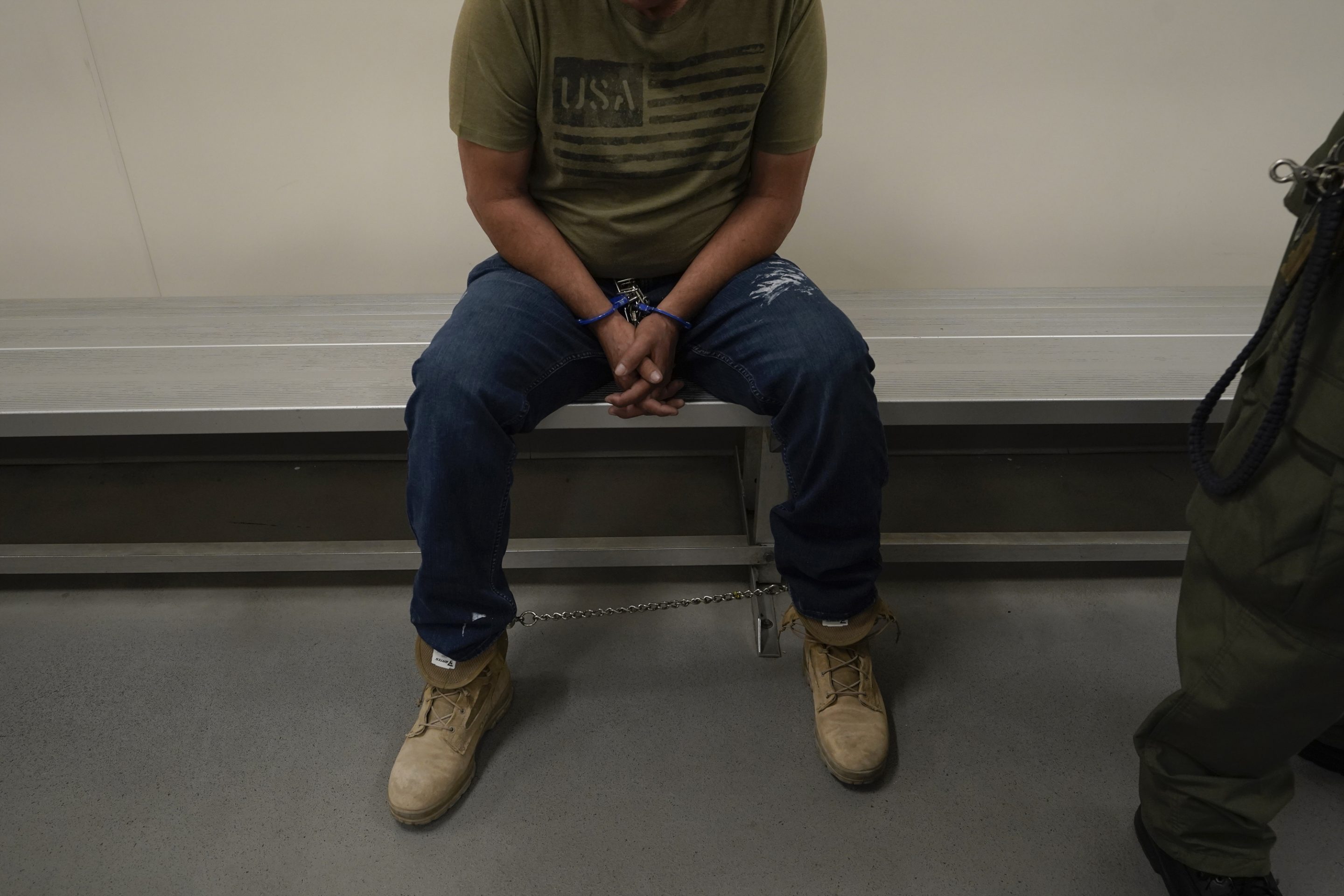 A person sitting on a bench with hands cuffed