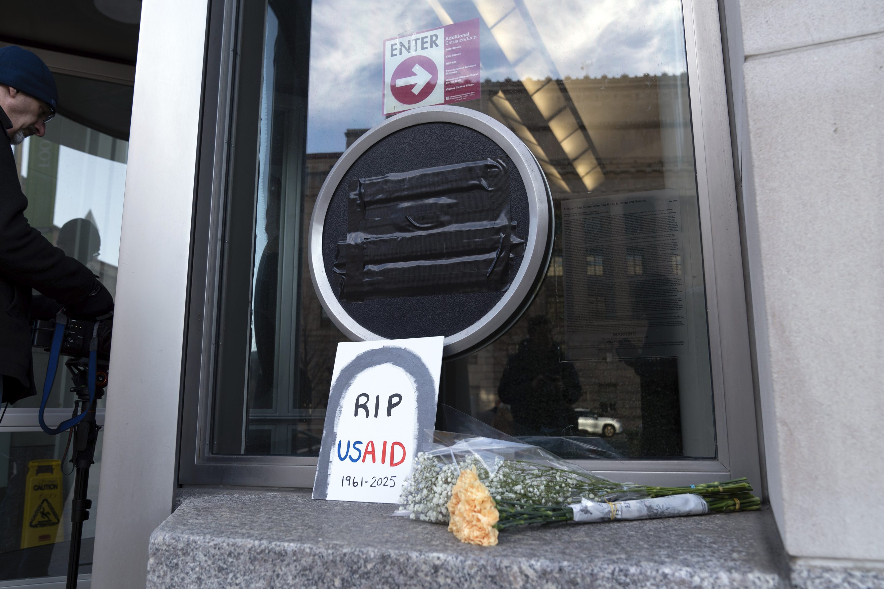 Flowers and a sign are placed outside the headquarters of the U.S. Agency for International Development, or USAID, on Feb. 7, 2025, in Washington.