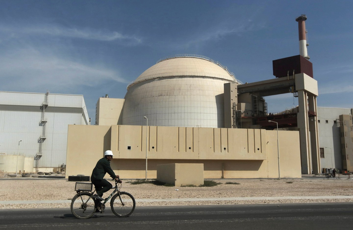 A man rides a bike in front of an Iranian nuclear reactor building