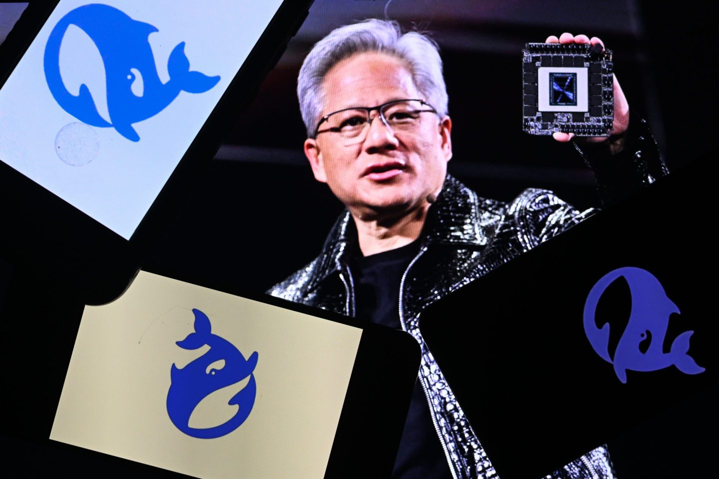 The DeepSeek logo is displayed on three cell phones in front of a computer screen showing Nvidia CEO Jensen Huang holding Nvidia's latest chip, on January 28, 2025, in Edmonton, Canada