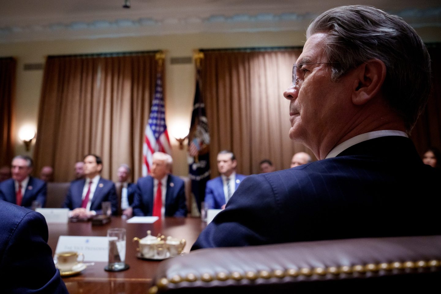 Treasury Secretary Scott Bessent looks to his left as Donald Trump sits opposite him during a Cabinet meeting.