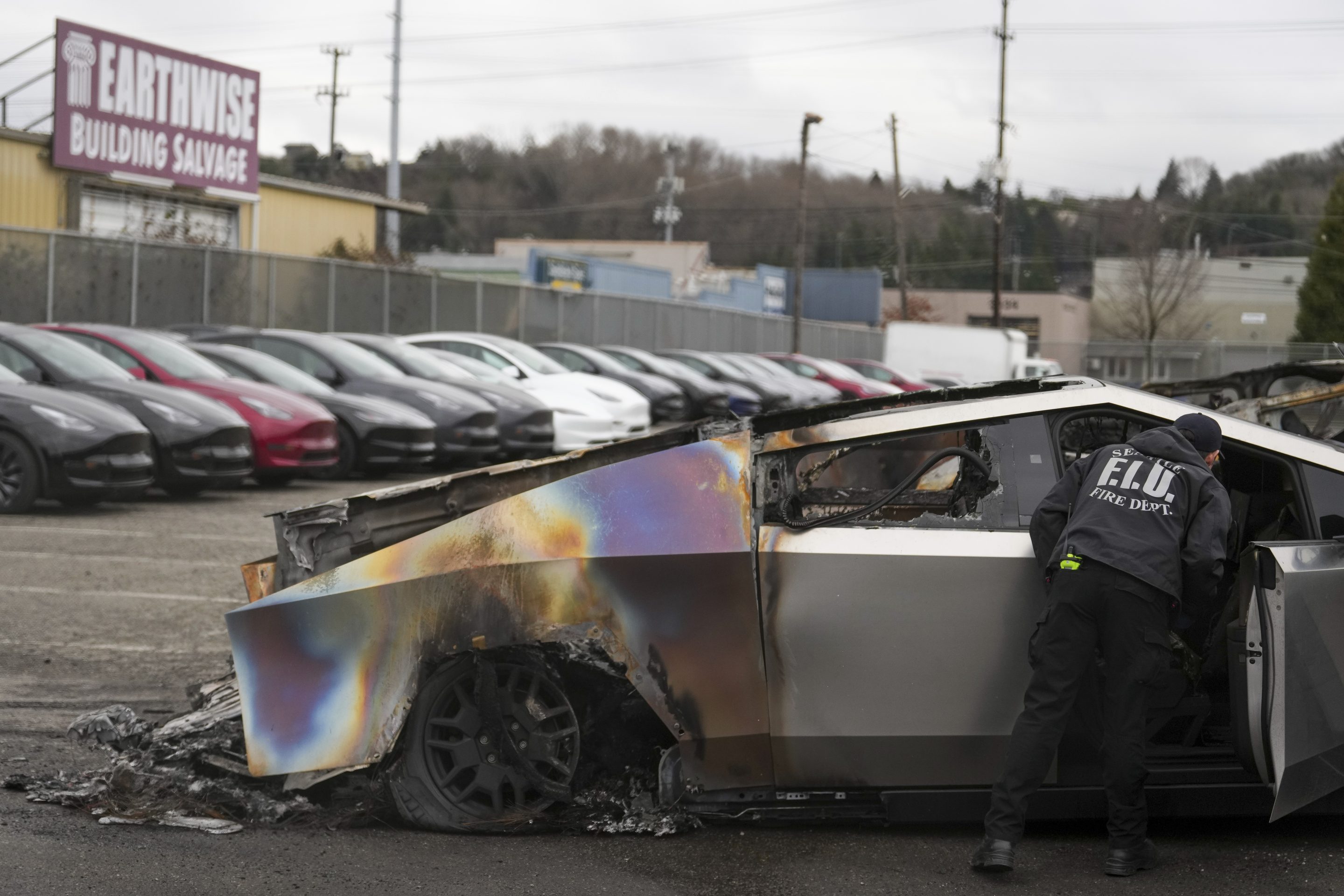 A member of the Seattle Fire Department inspects a burned Tesla Cybertruck at a Tesla lot in Seattle, on March 10, 2025.
