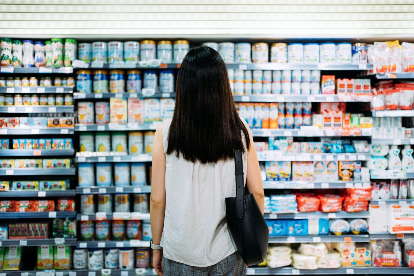 Woman standing in front of shelves of infant formula in a store