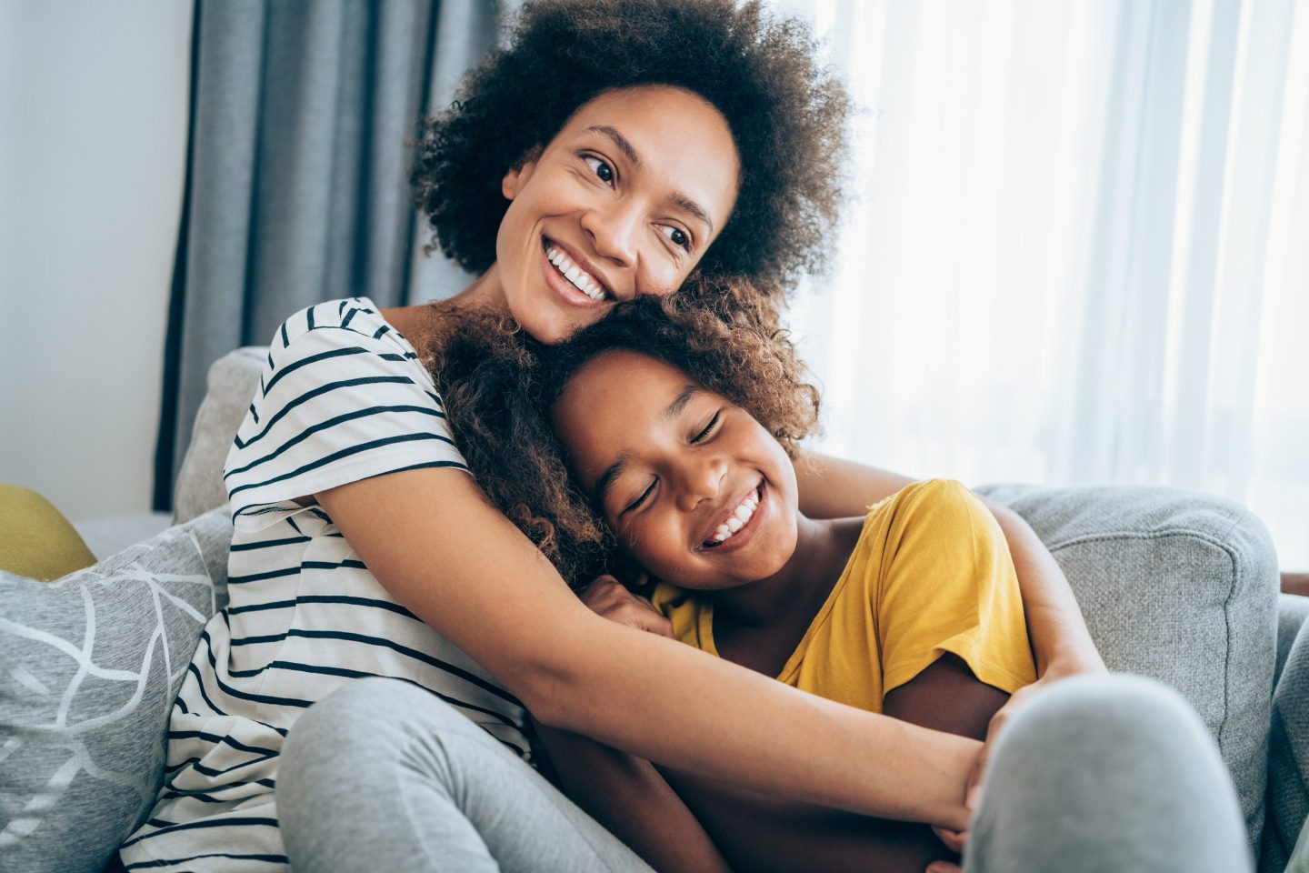 Mom sitting with her arms around her kid who looks to be around 10 years old