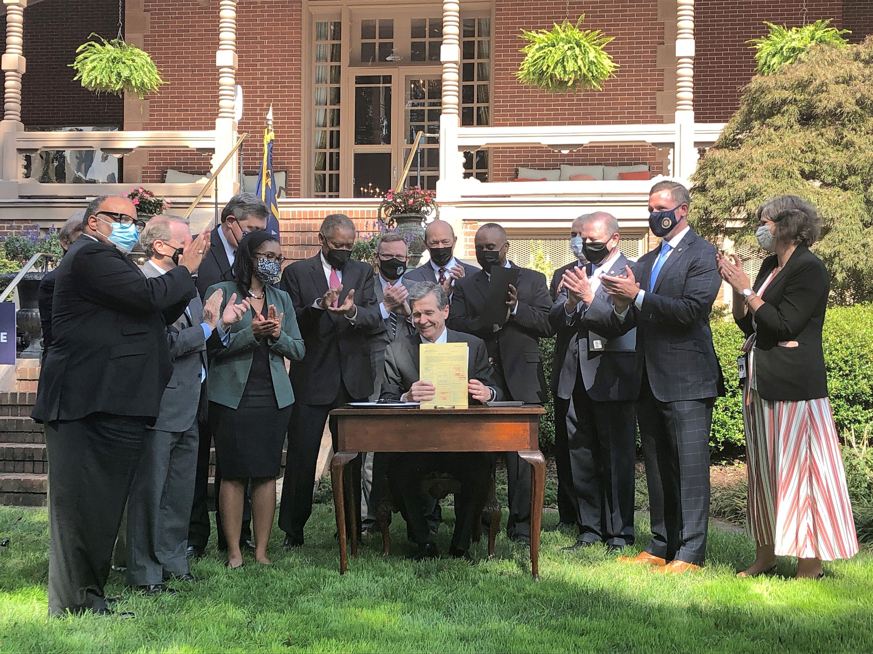 North Carolina Gov. Roy Cooper completes signing into law a major energy bill as several legislators and an aide applaud during an Executive Mansion ceremony in Raleigh, N.C, Oct. 13, 2021.