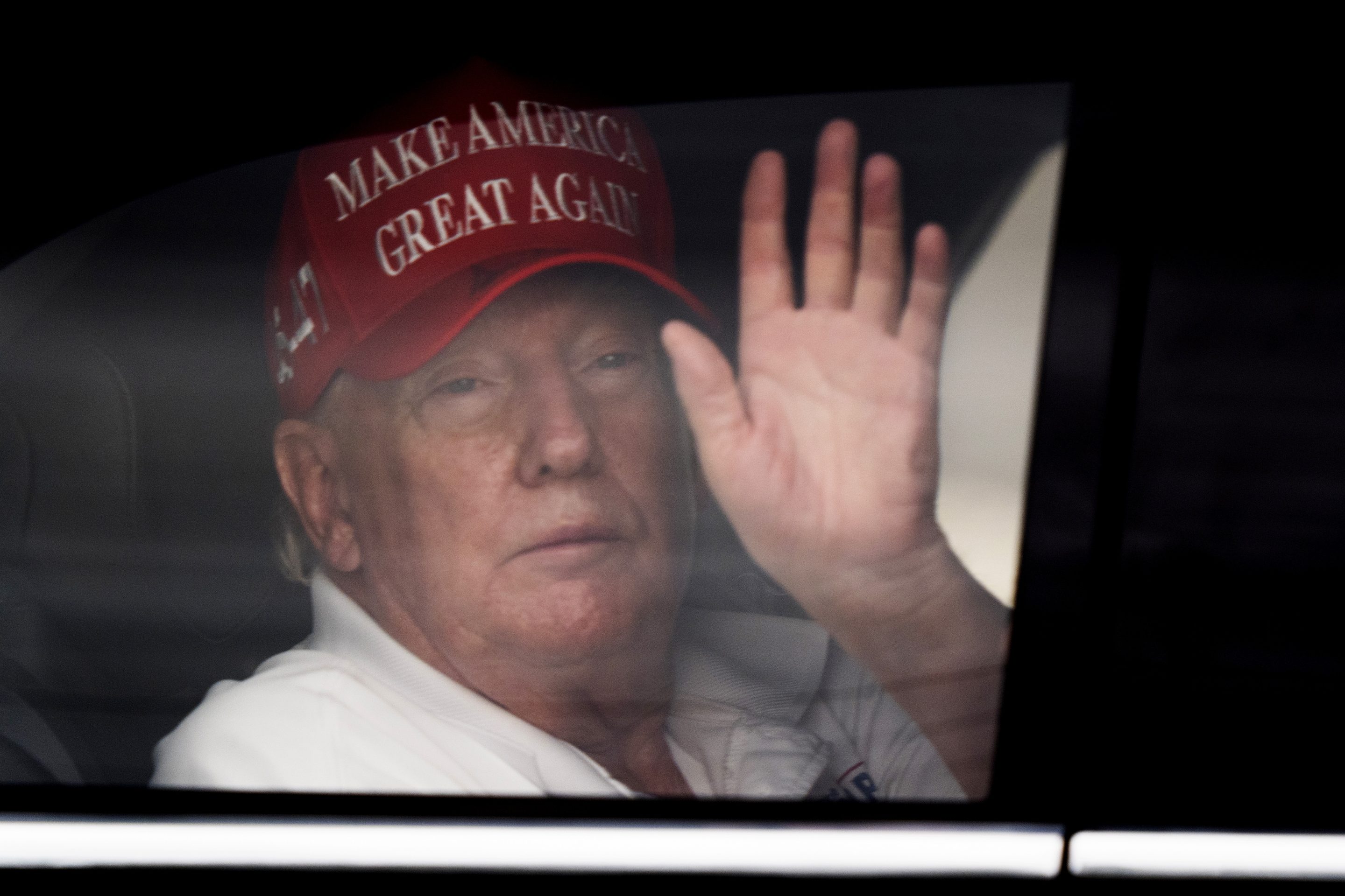 President Donald Trump waves to supporters from his limousine as he arrives at Trump International Golf Club, on March 29, 2025, in West Palm Beach, Fla.