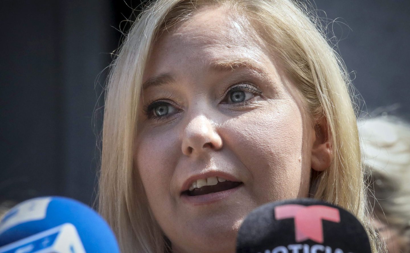 Virginia Giuffre speaks in front of microphones