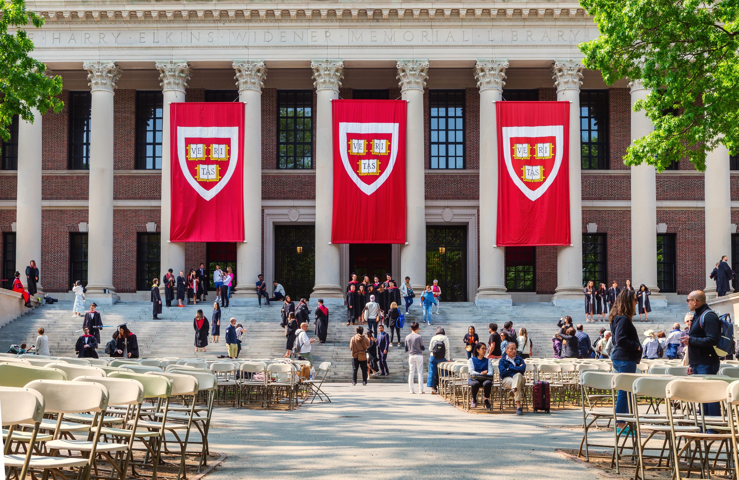 Students in graduation gowns and their families in front of the Harry Elkins Widener Memorial Library, at Harvard.