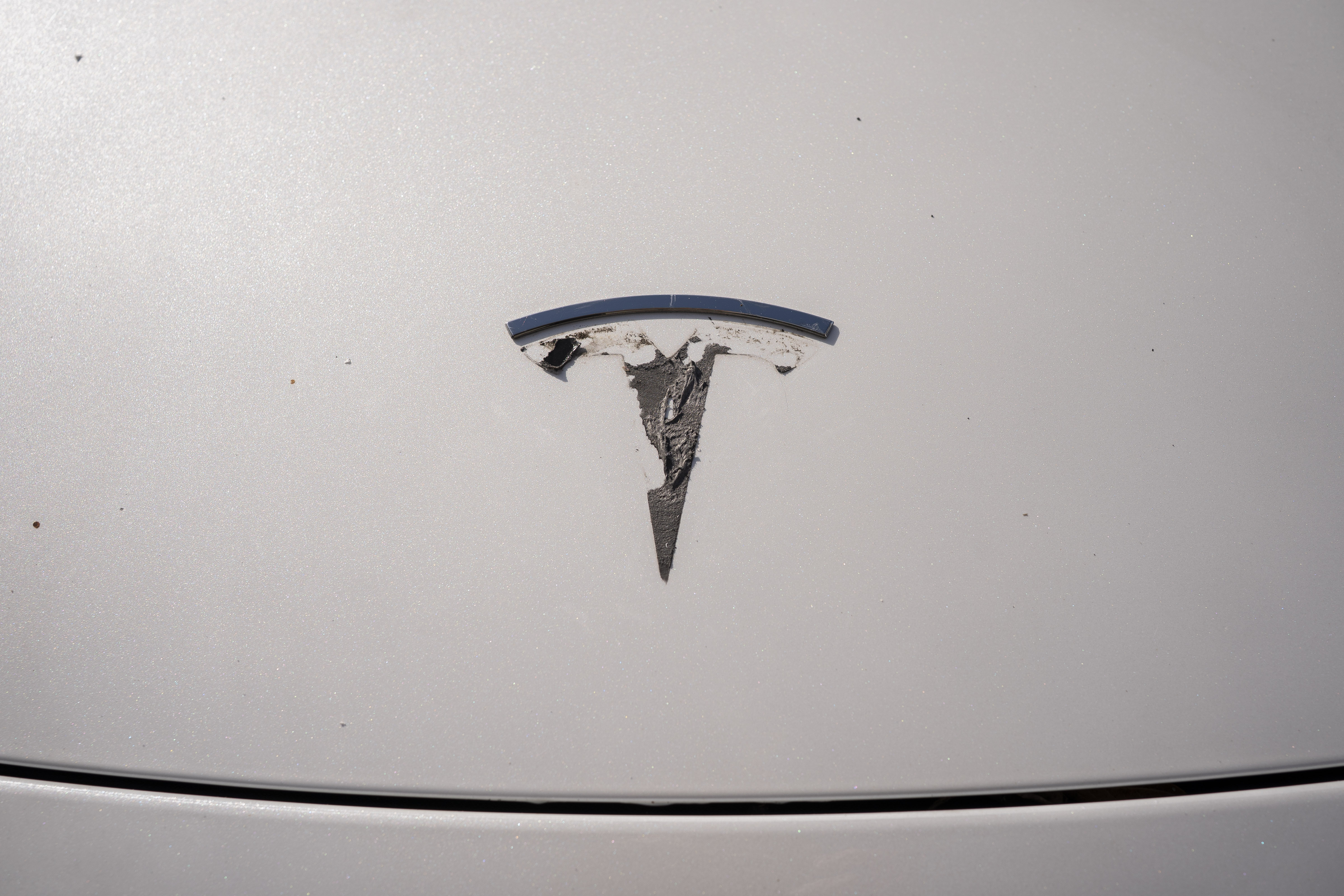 A Tesla emblem is being removed from a vehicle during a "de-badging" event on April 12, 2025 in Seattle, Washington. (Photo: David Ryder/Getty Images)