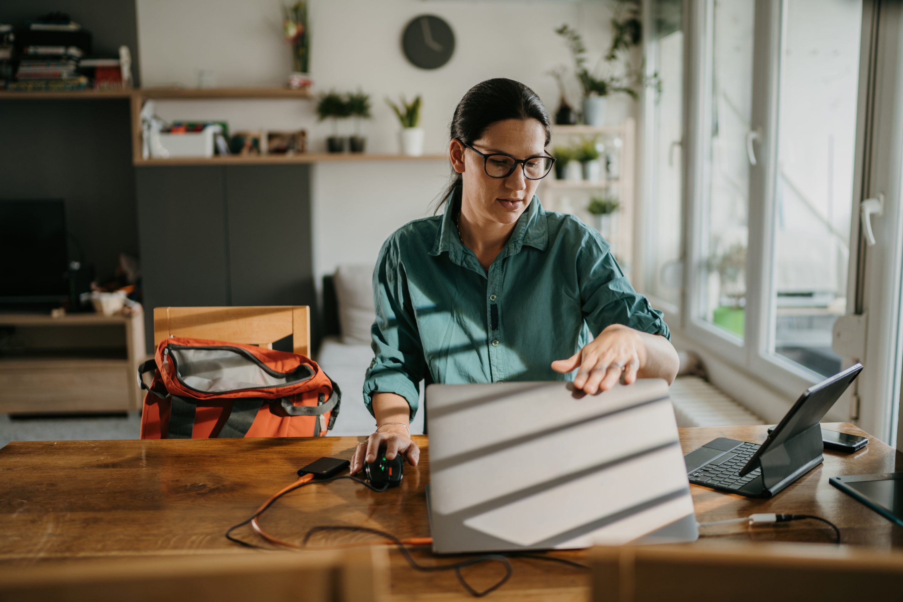 A woman sitting at a desk closes her laptop.