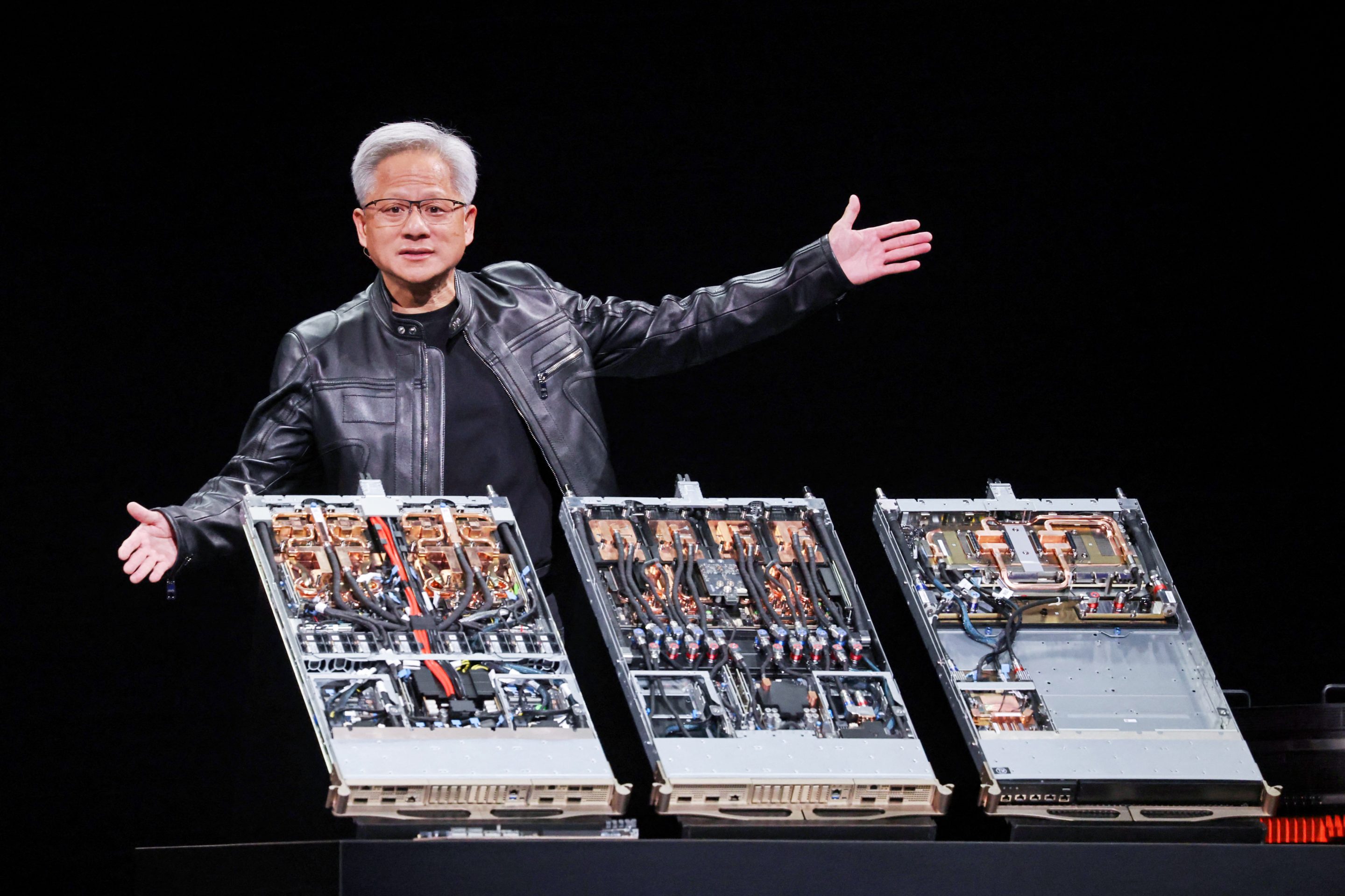 Jensen Huang spreads his hands over a display of giant computer chips as he gives a speech.