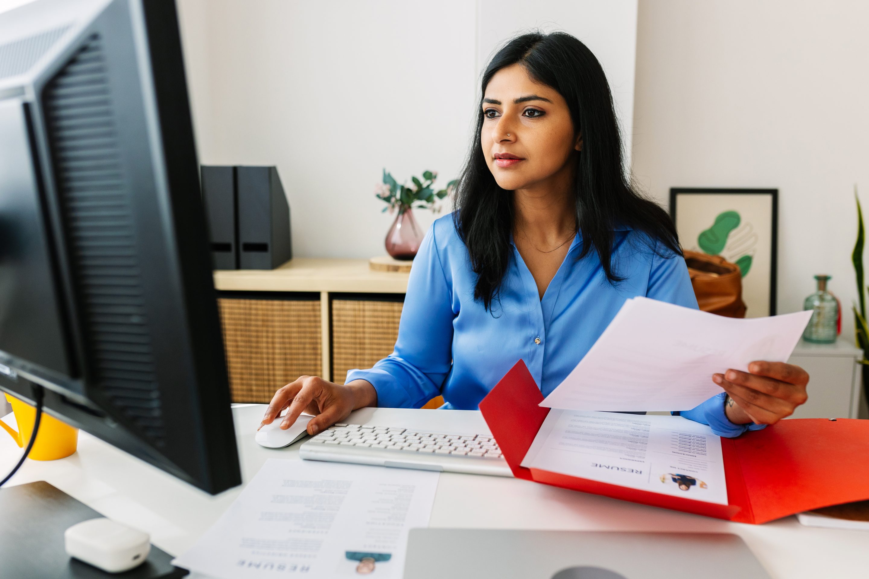 Professional HR manager reading job candidate’s resume in her office while working on laptop. Recruitment human resources employment hiring concept.