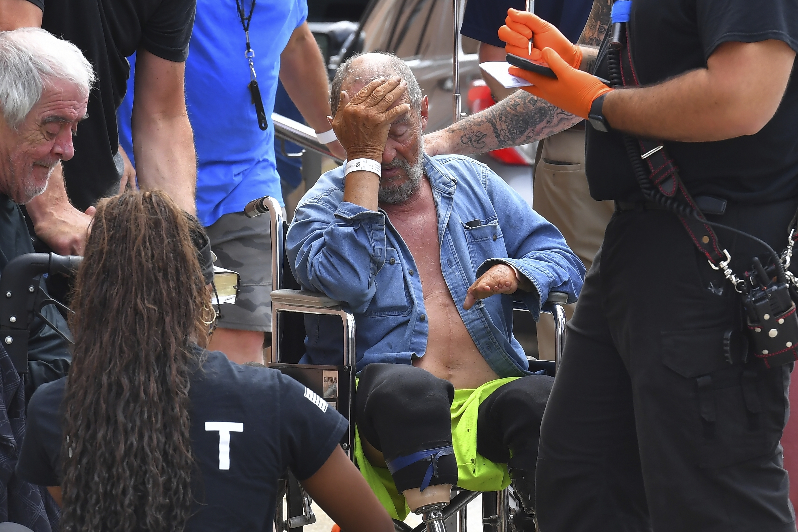 Michael Pimentel, center, a resident at the Gabriel House assisted living facility, in Fall River, Mass., receives assistance from an emergency medical worker, right, outside a temporary shelter, on July 14, 2025, in Fall River, following a fire that started late Sunday. 