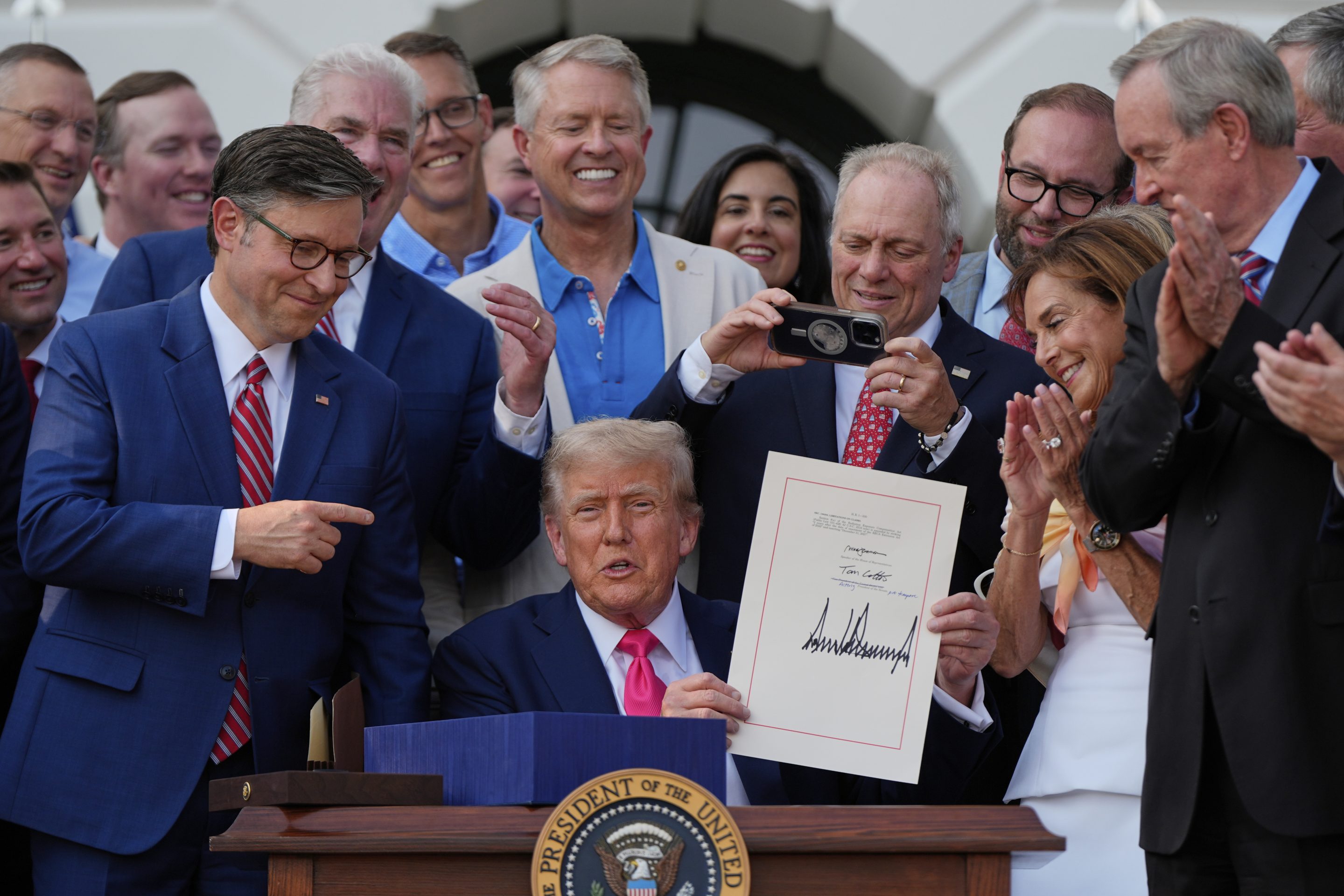 resident Donald Trump holds his signed signature bill of tax breaks and spending cuts at the White House, July 4, 2025, in Washington.