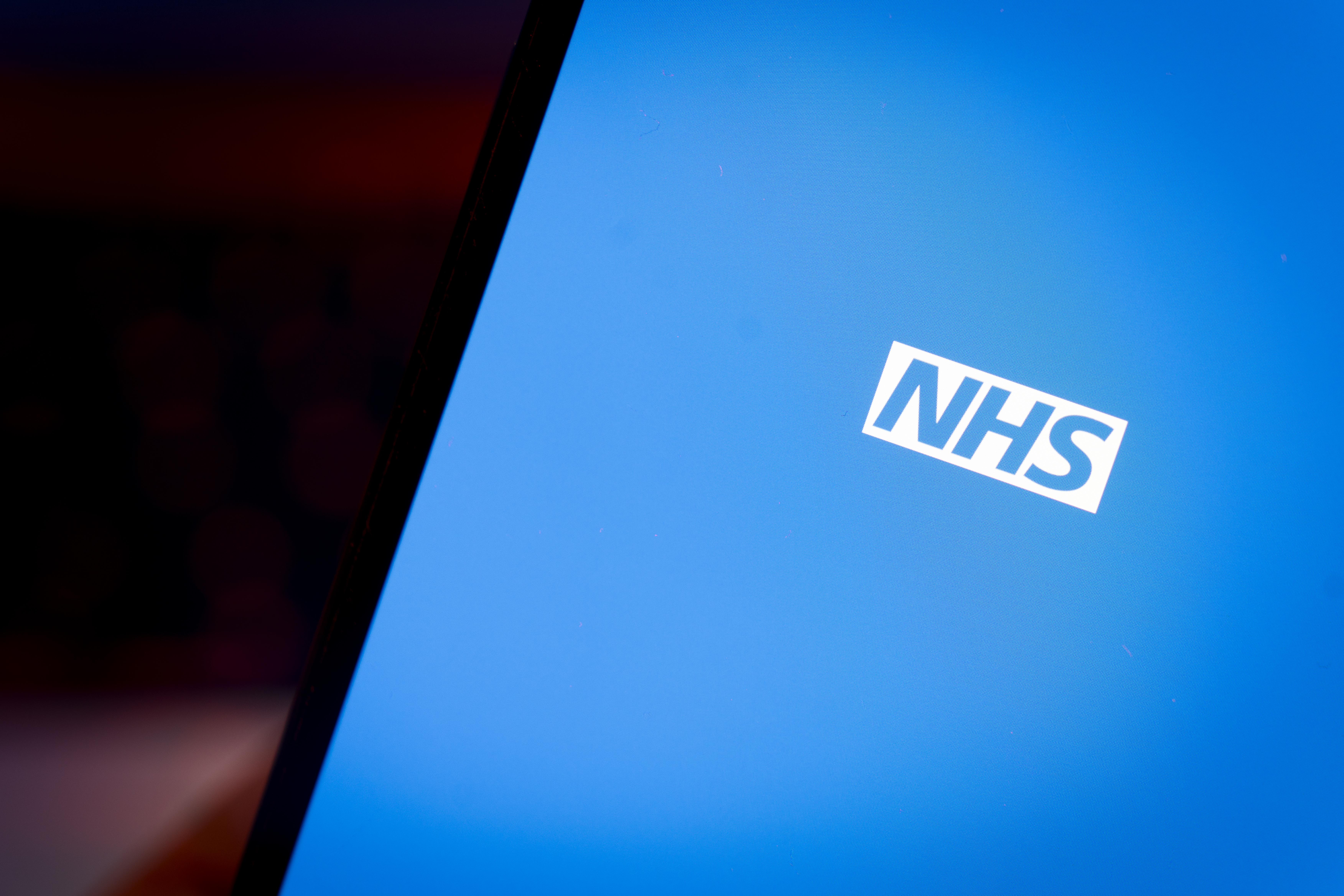 NHS logo on a phone screen.