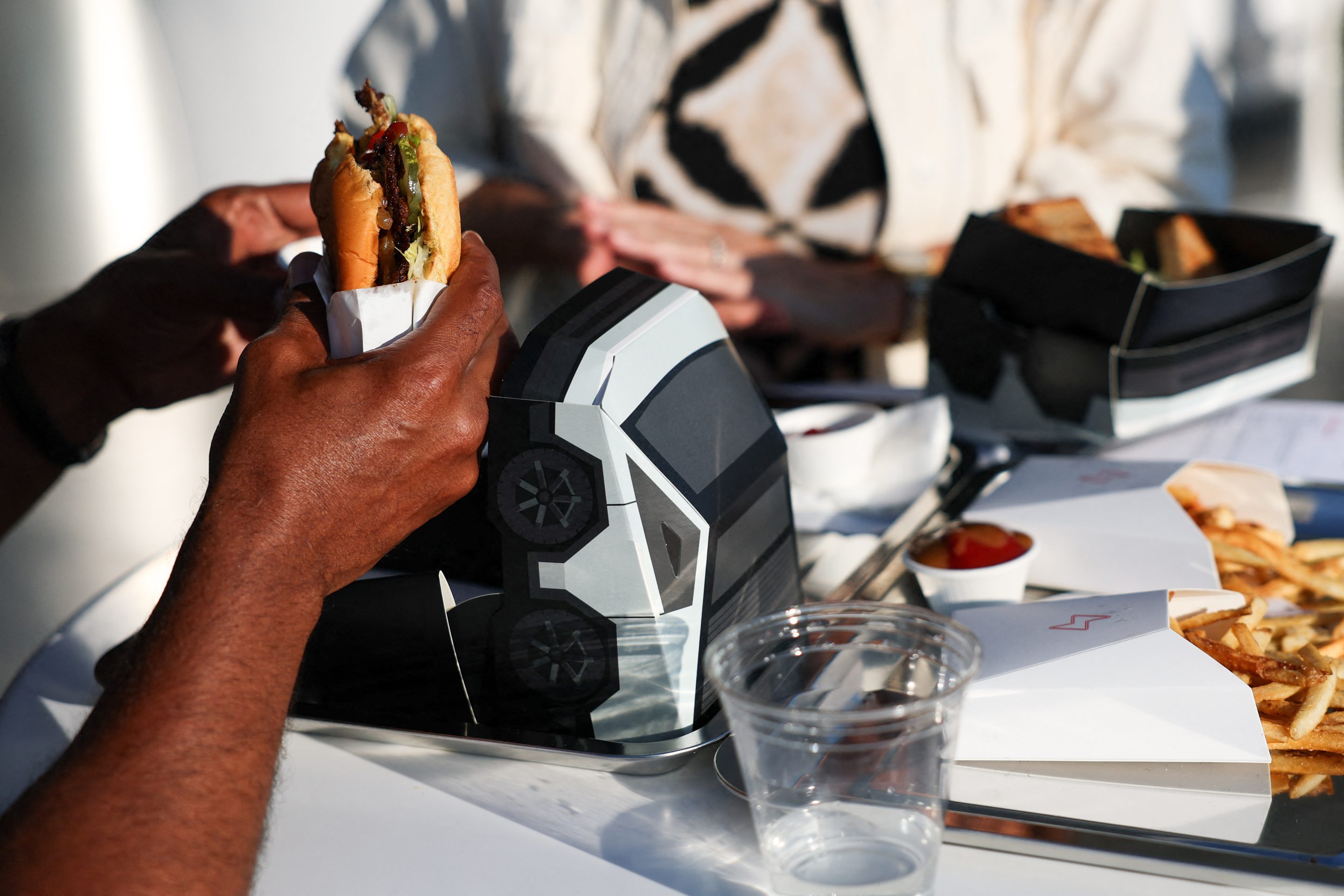 An attendee eats the Tesla burger from a Cybertruck-inspired box during the opening of the Tesla Diner in Los Angeles on July 21. The retro-futuristic restaurant serves up diner classics, including “epic bacon,” tallow-fried french fries, and hot dogs.