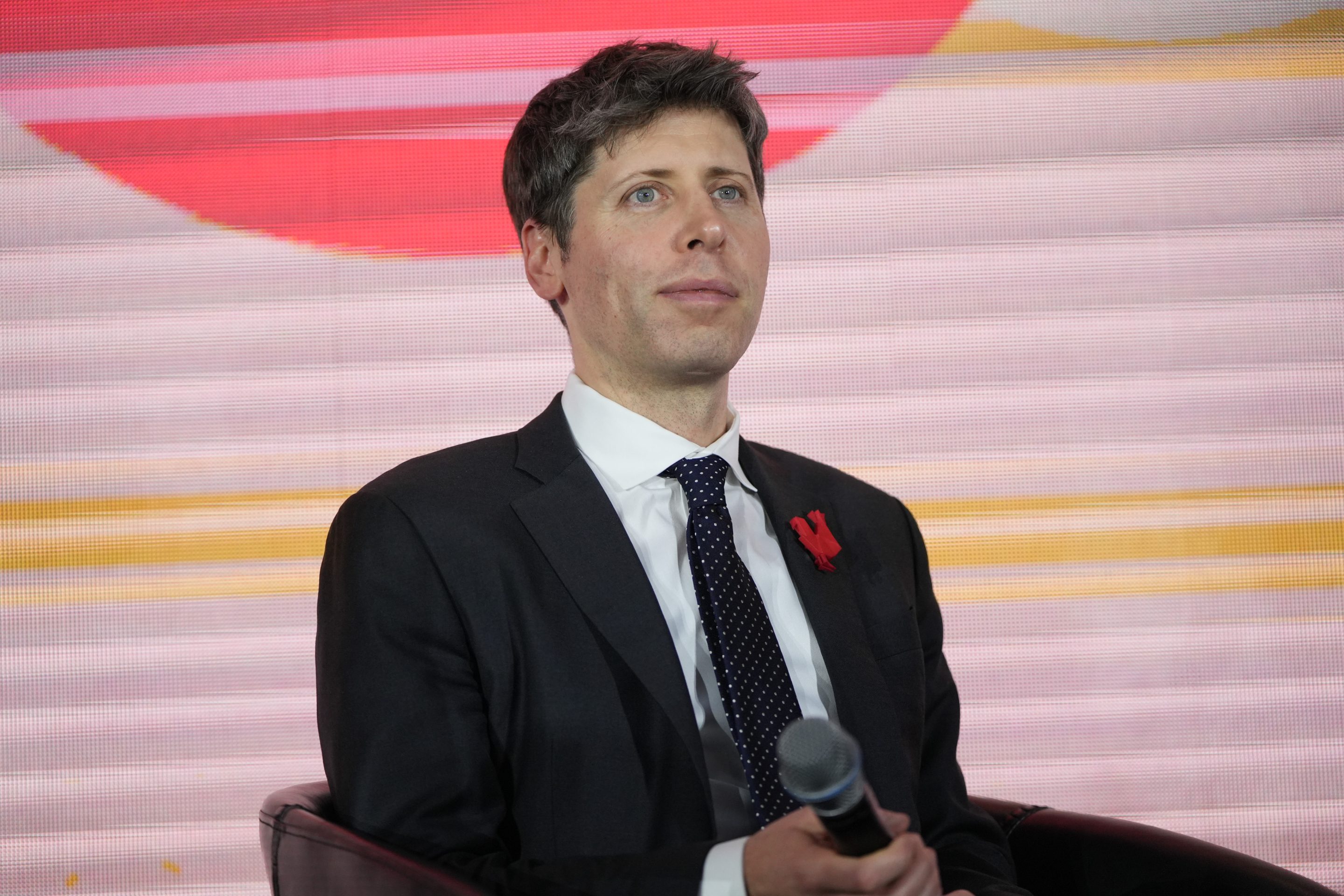 Sam Altman sits and smiles