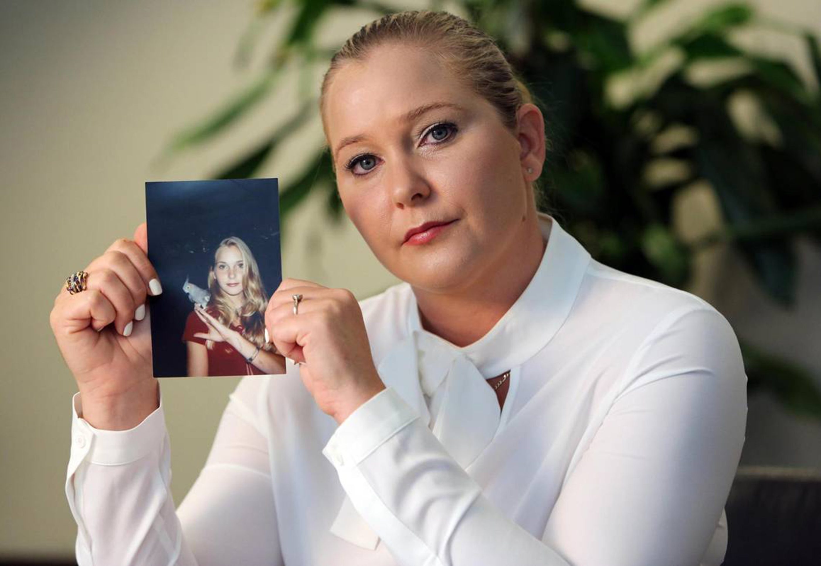 Virginia Giuffre holds a photo of herself as a teen