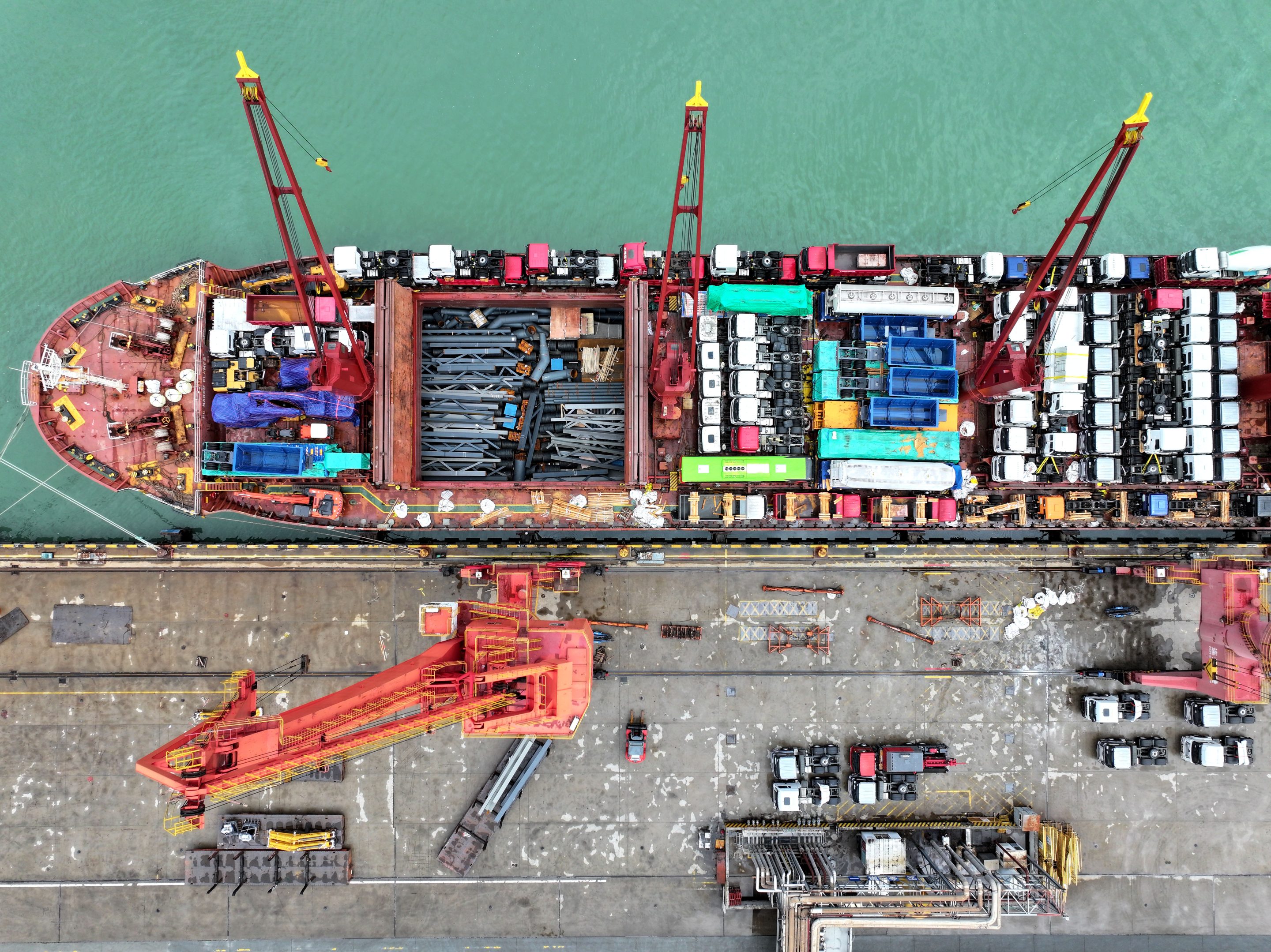Vehicles and machinery are loaded onto ships at Lianyungang Port in China for export overseas.