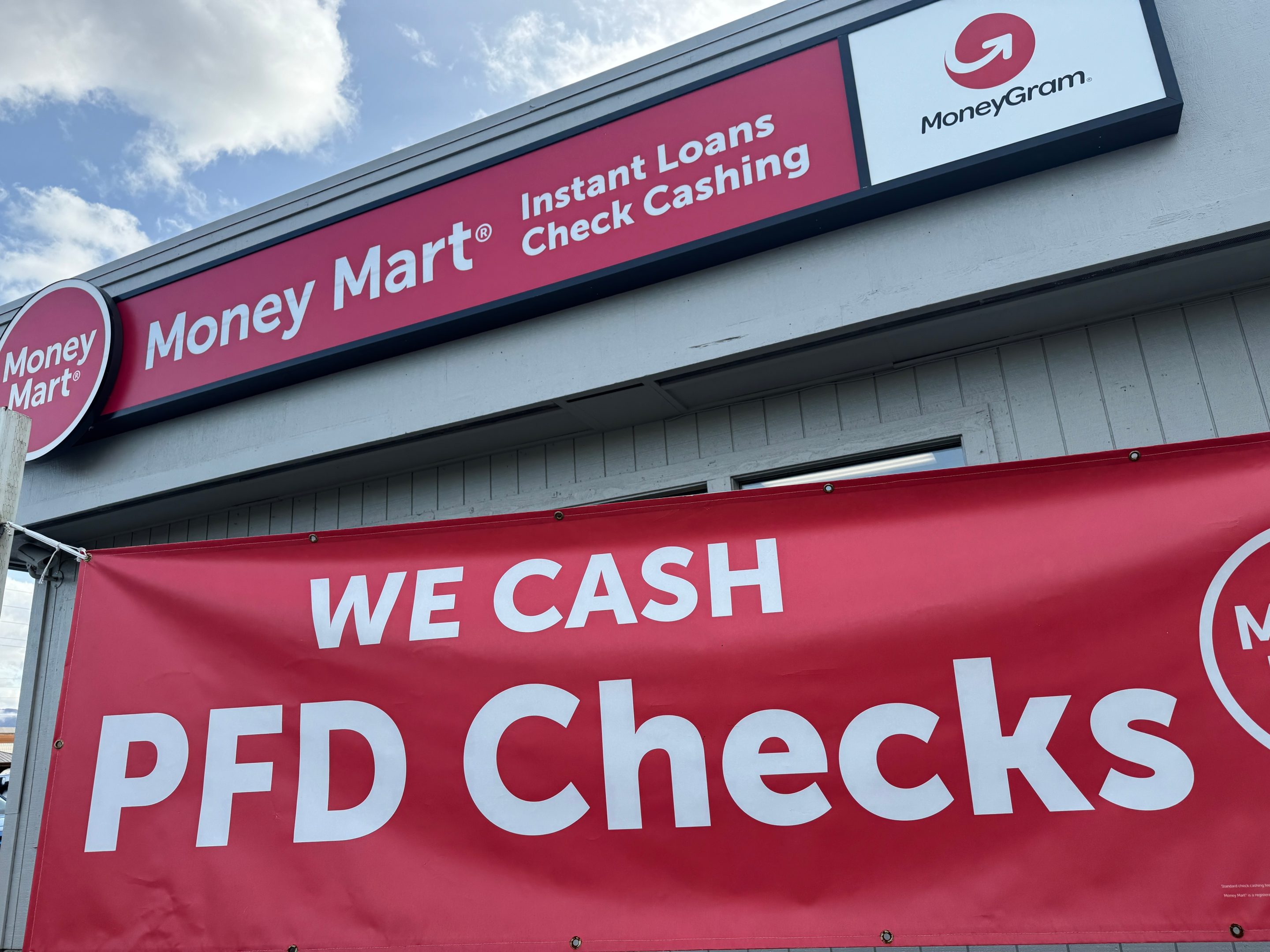 A sign advertising the cashing of Alaska Permanent Fund Dividend, or PFD, checks hangs outside a business in Anchorage on Sept. 23.