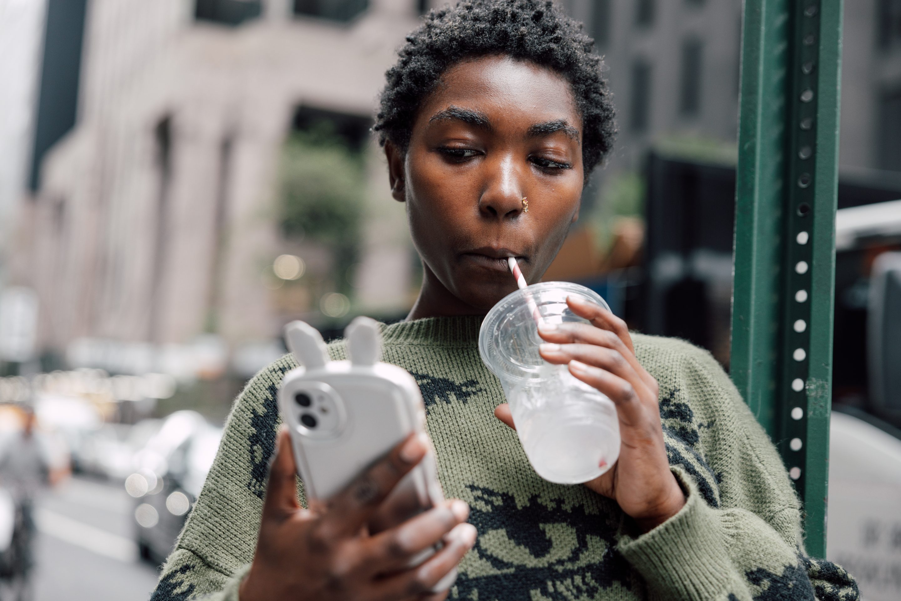 A Gen Zer sipping a soda, looking at their phone