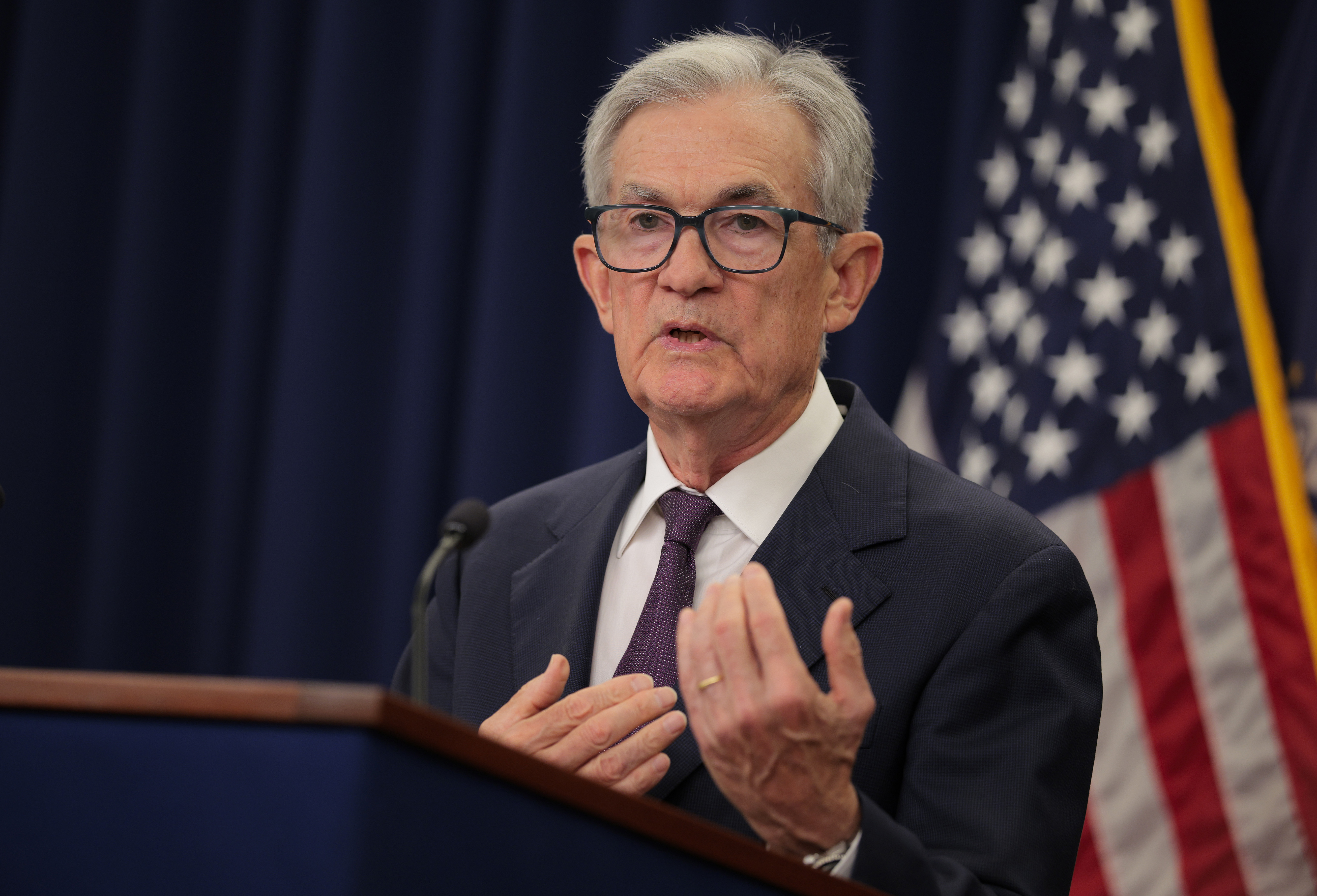 Federal Reserve Chair Jerome Powell in a dark suit at a podium.