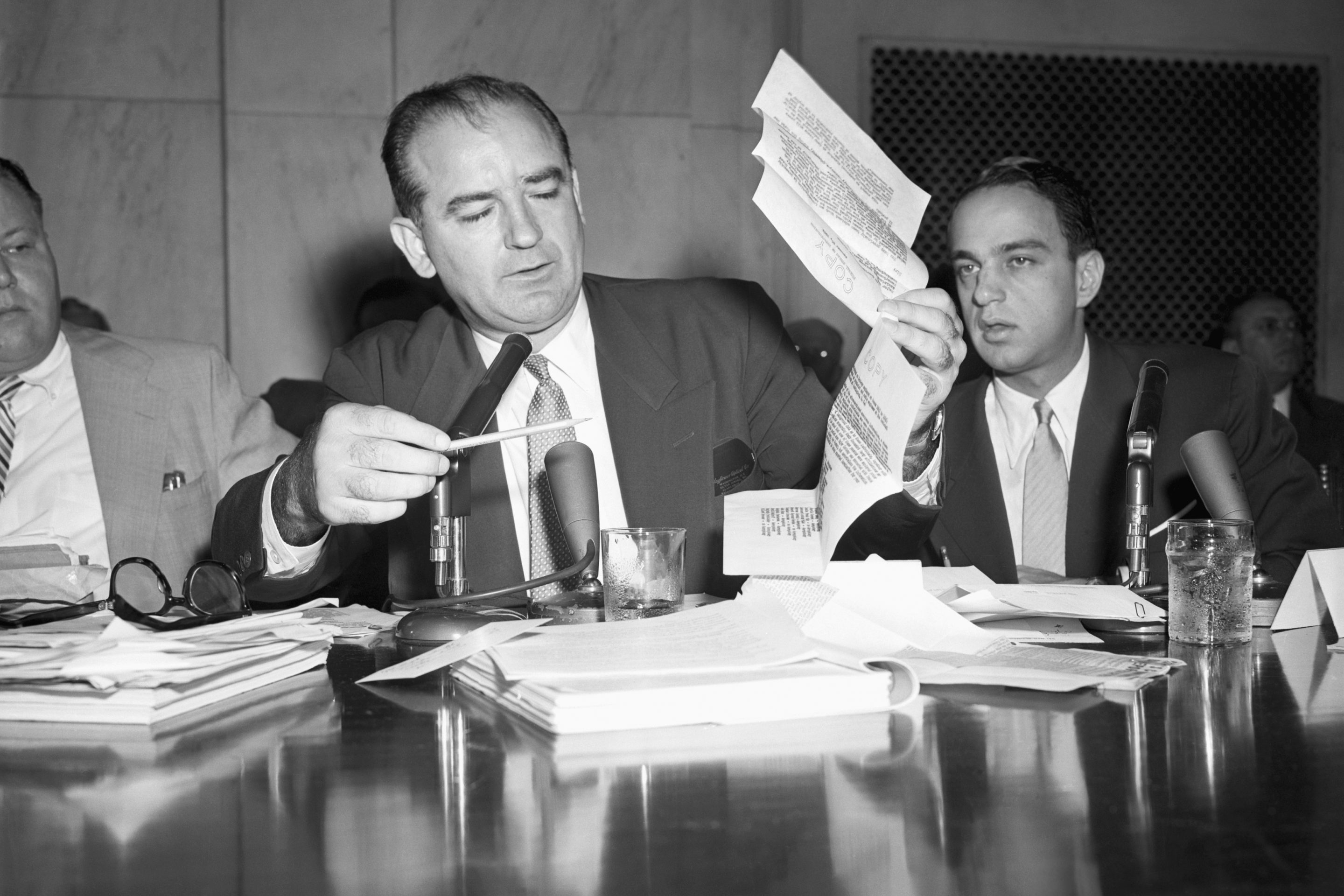 Sen. Joseph McCarthy holds up a letter purportedly written by FBI Director Hoover in 1941, warning that a Fort Monmouth employee had a "direct connection with an espionage agent." Attorney Roy Cohn sits to the right of McCarthy.