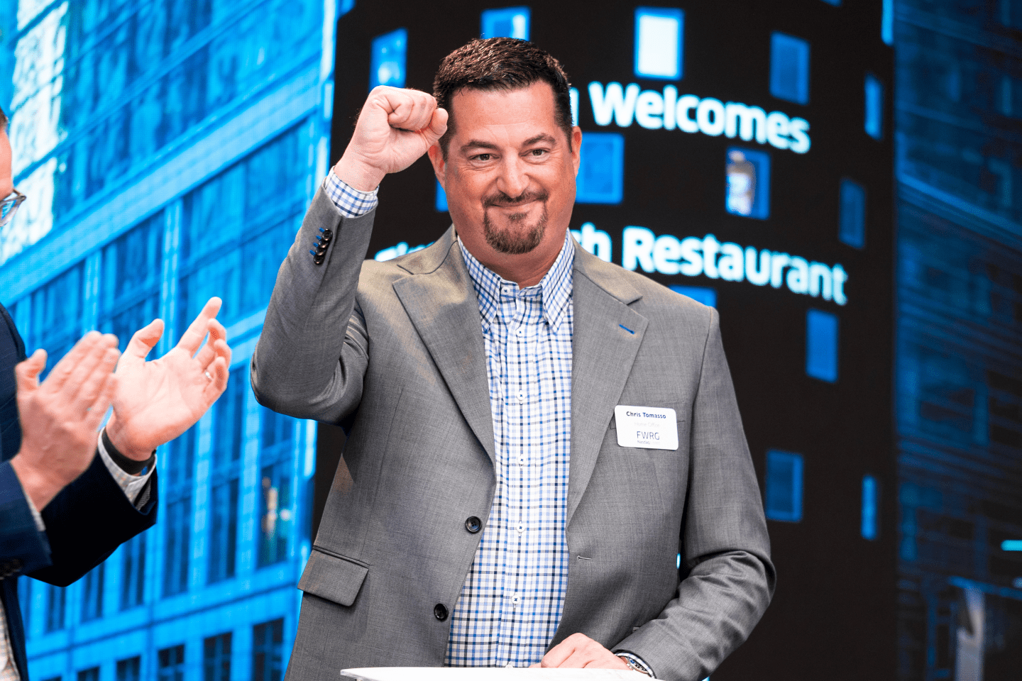 First Watch CEO Chris Tomasso holding his fist up at the New York Stock Exchange