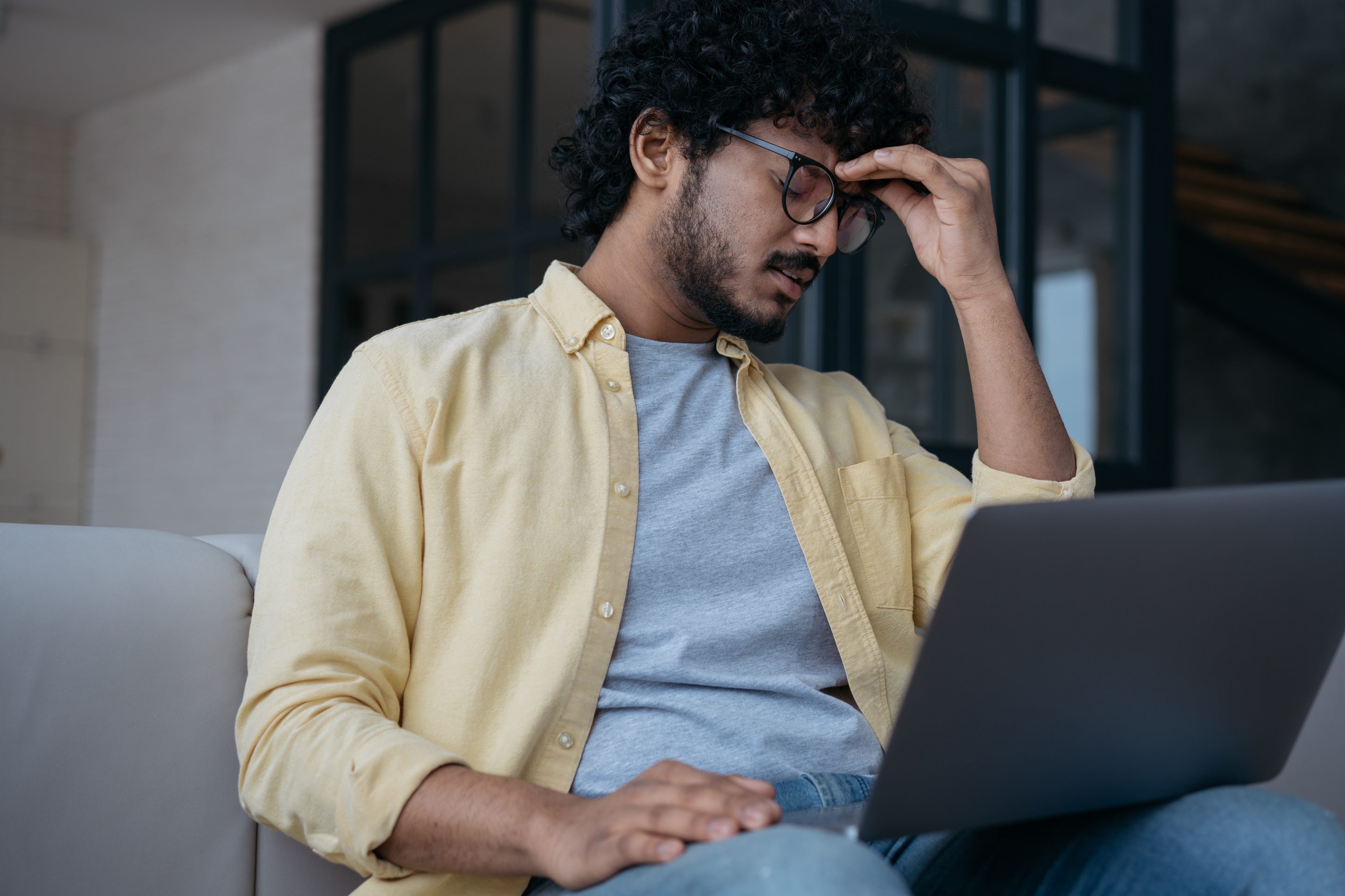 Tired stressed Indian businessman having headache sitting in office. Man fired from work.
