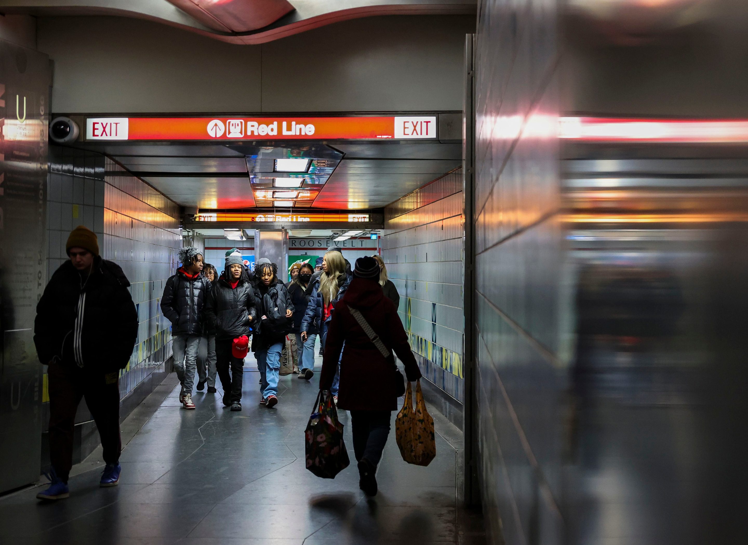 Riders walk to and from the Red Line stop in the Roosevelt CTA station on Dec. 19, 2023, in Chicago.