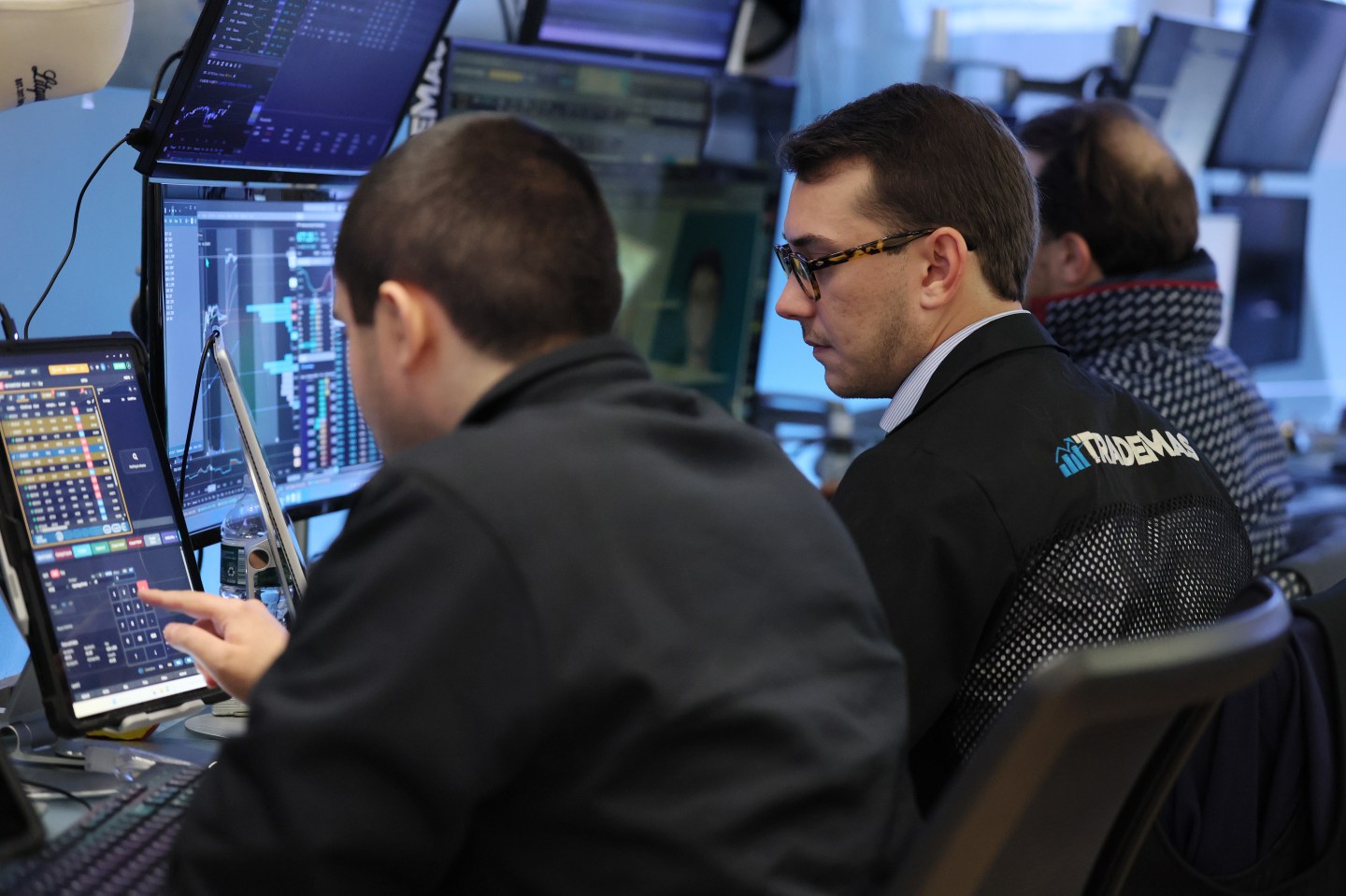 Two men are looking at monitors while trading