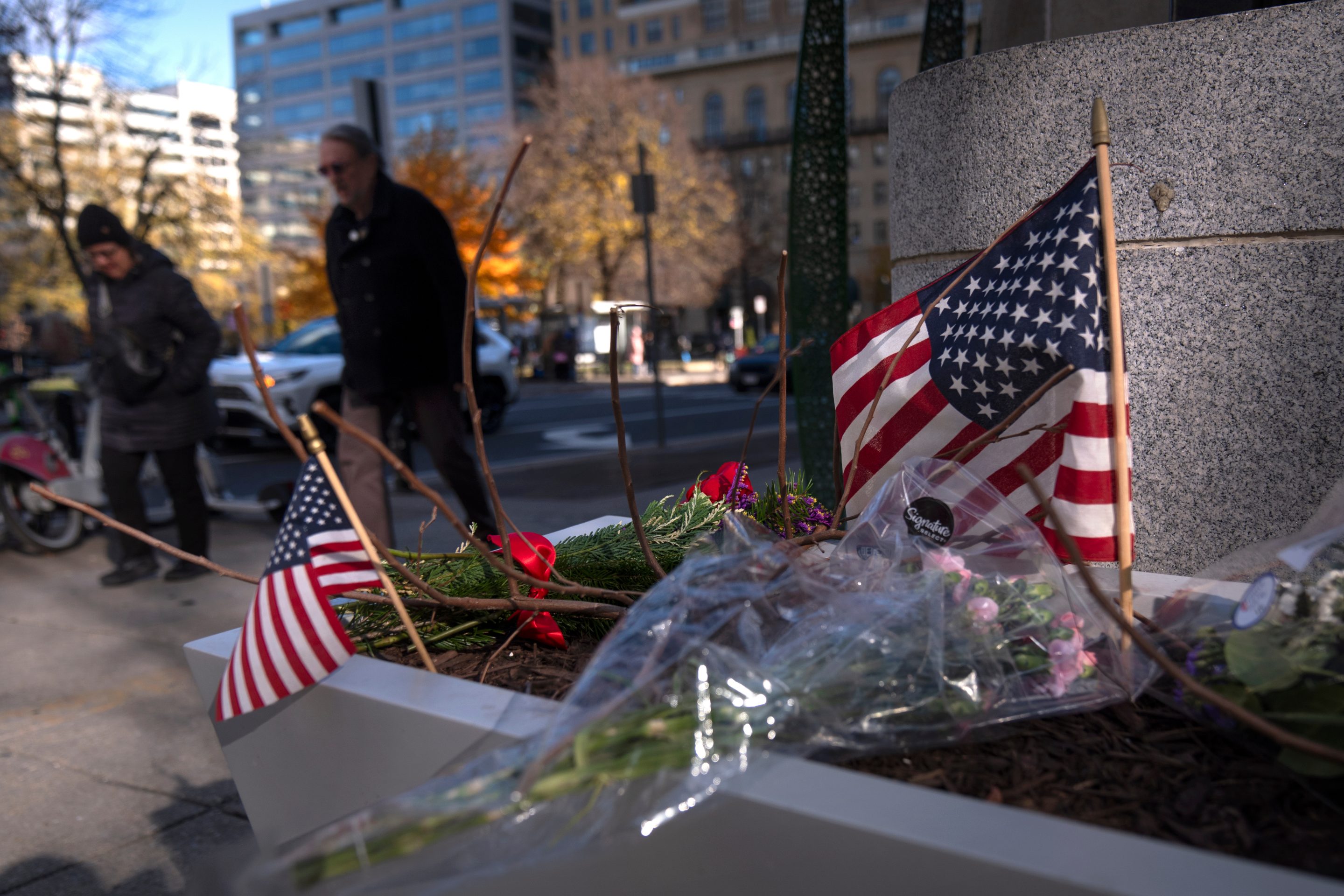 People walk past a small memorial in a planter, Friday, Nov. 28, 2025, near the site where two National Guard members were shot in Washington.