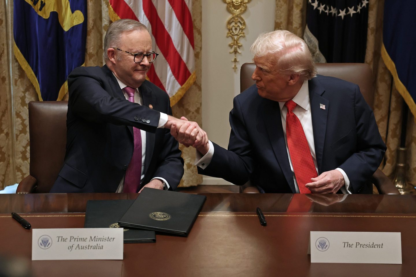 Prime Minister of Australia Anthony Albanese (L) and U.S. President Donald Trump shake hands after signing a $8.5 billion rare earth minerals agreement during a bilateral meeting in the Cabinet Room of the White House on October 20, 2025 in Washington, DC.