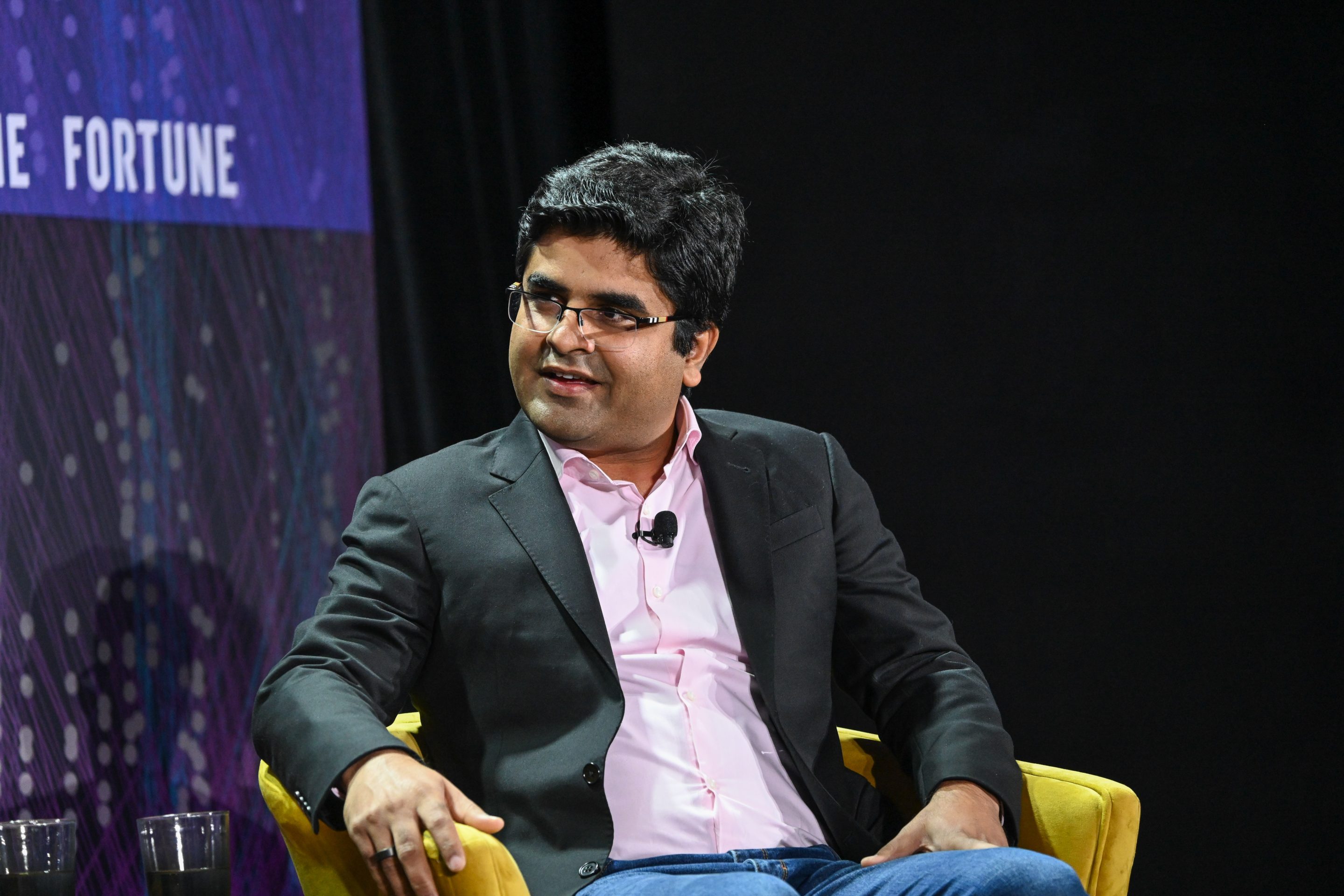 Prakhar Mehrotra smiles as he sits in a yellow chair onstage with "Fortune" on the background screen.