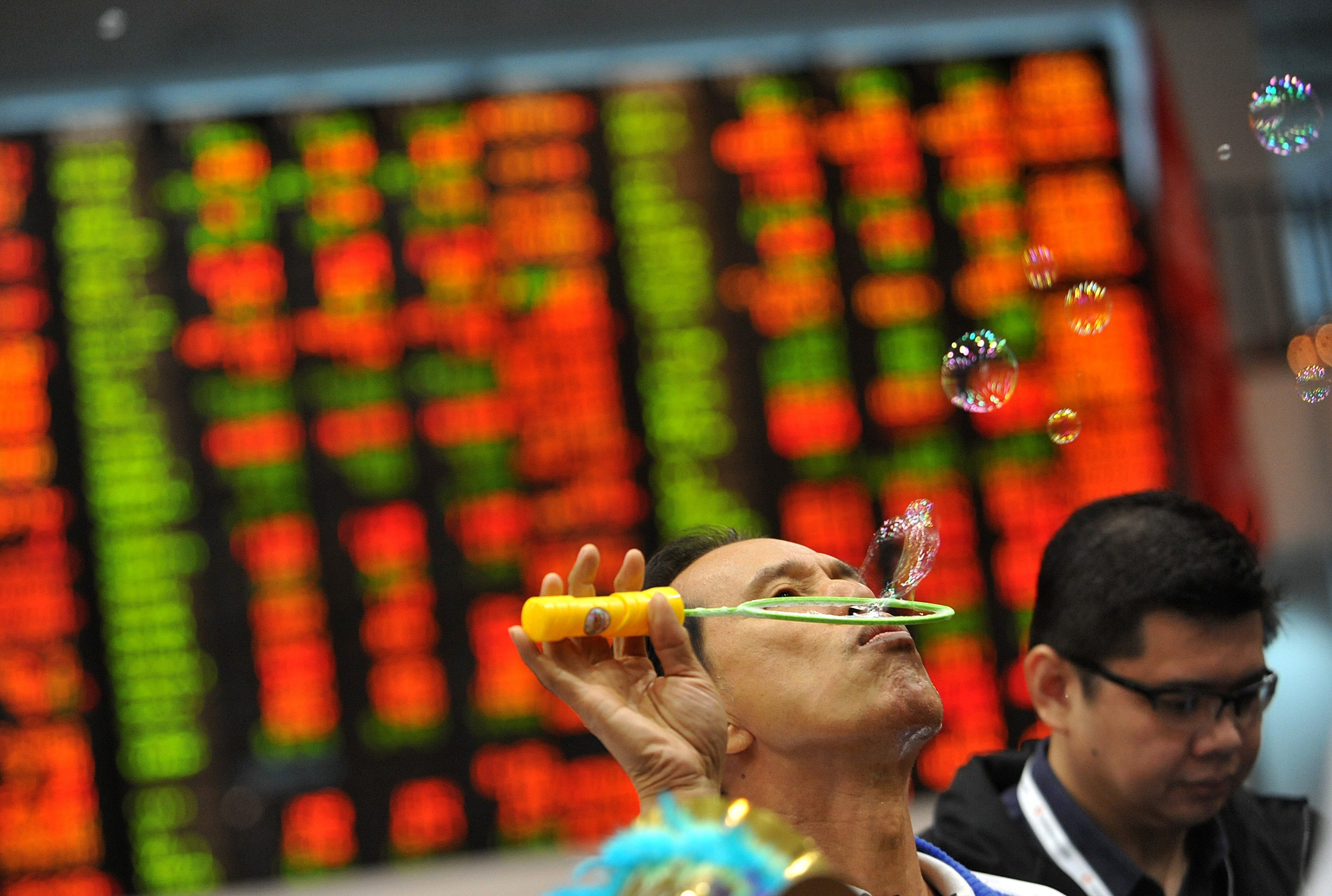 A trader blows bubbles during the year-end closing of trade in front of a giant electronic board at the Philippine Stock Exchange in Manila on December 30, 2010.