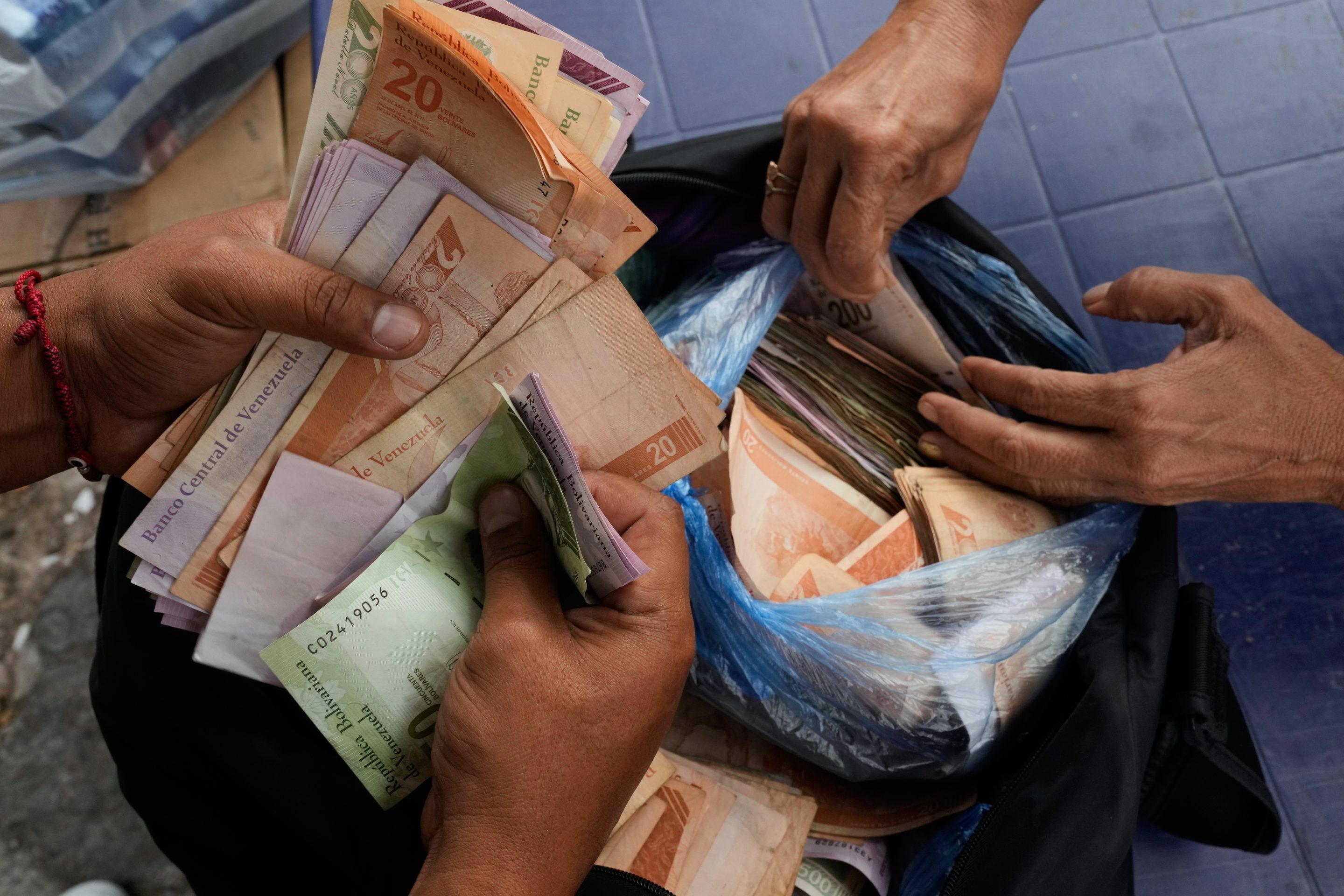 People exchange U.S. dollars for Venezuelan bolivars at a street market in Caracas, Venezuela, Thursday, Jan. 8, 2026.