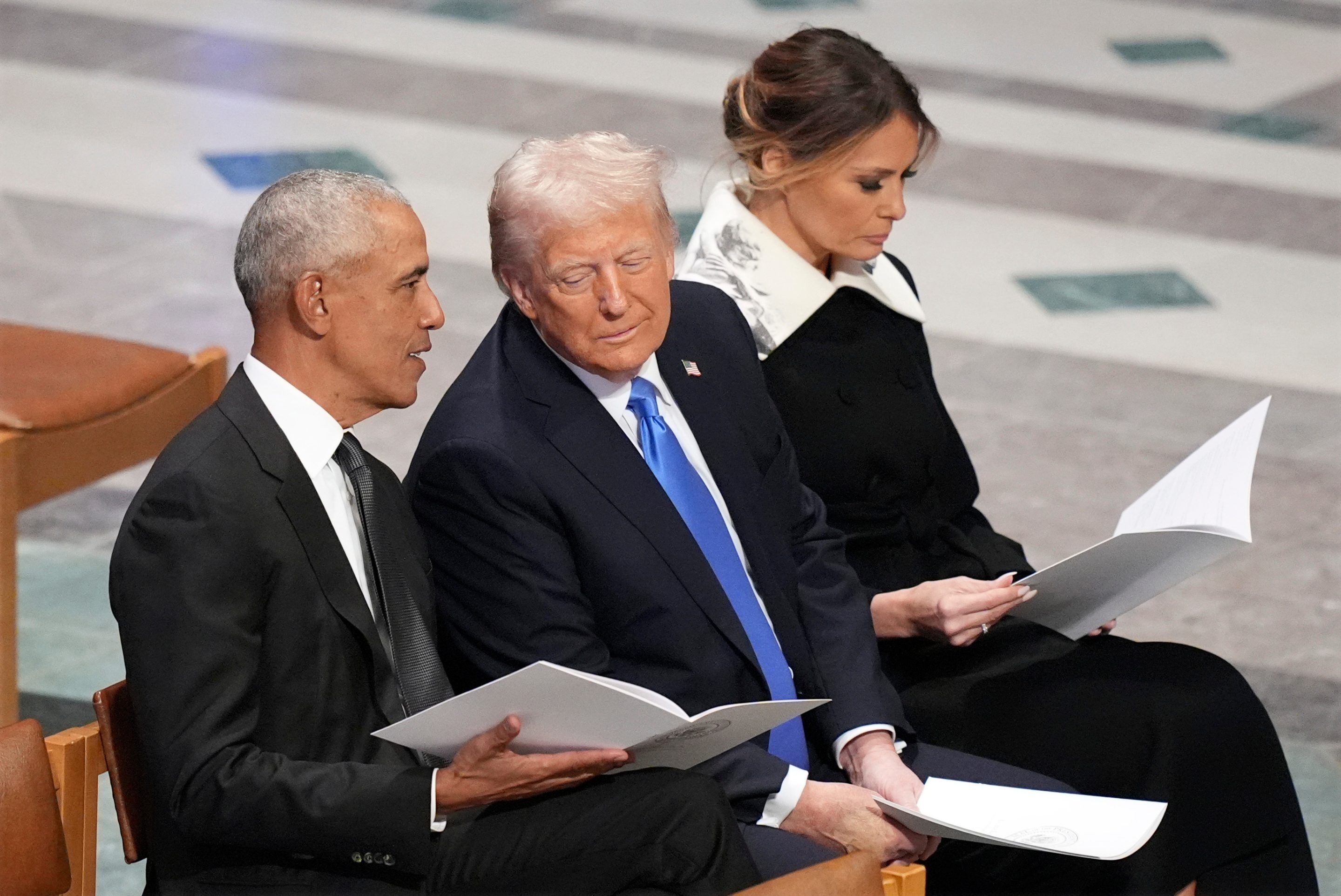 Former President Barack Obama talks with then President-elect Donald Trump as Melania Trump reads the funeral program before the state funeral for former President Jimmy Carter at Washington National Cathedral in Washington, Jan. 9, 2025.