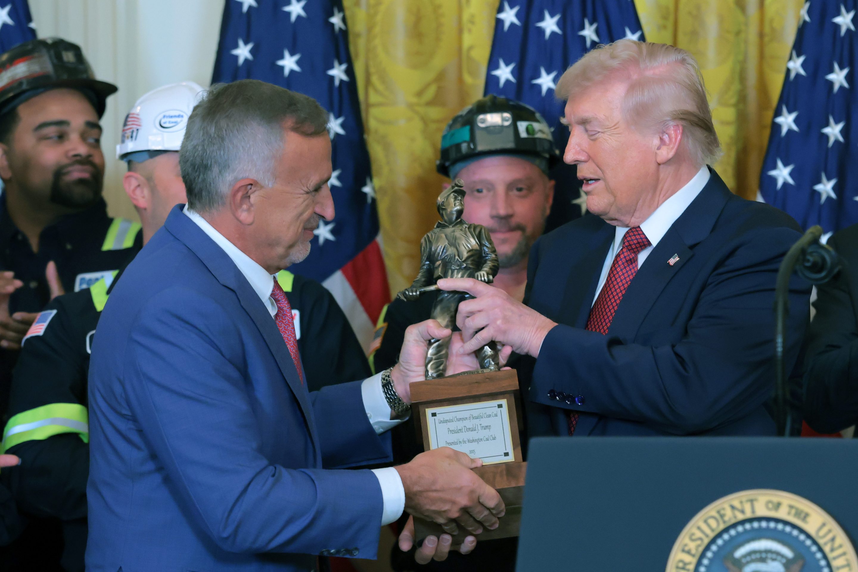 The CEO of coal producer Peabody Energy, Jim Grech, left, hands a trophy to U.S. President Donald Trump during an event on the use of coal in the East Room of the White House on Feb. 11, 2026 in Washington, DC. The lobbyist group, the Washington Coal Club, awarded Trump the inaugural "Undisputed Champion of Coal" award. Trump also is signing an executive order directing the Defense Department to buy electricity from coal-fired power plants. (Photo by Anna Moneymaker/Getty Images)
