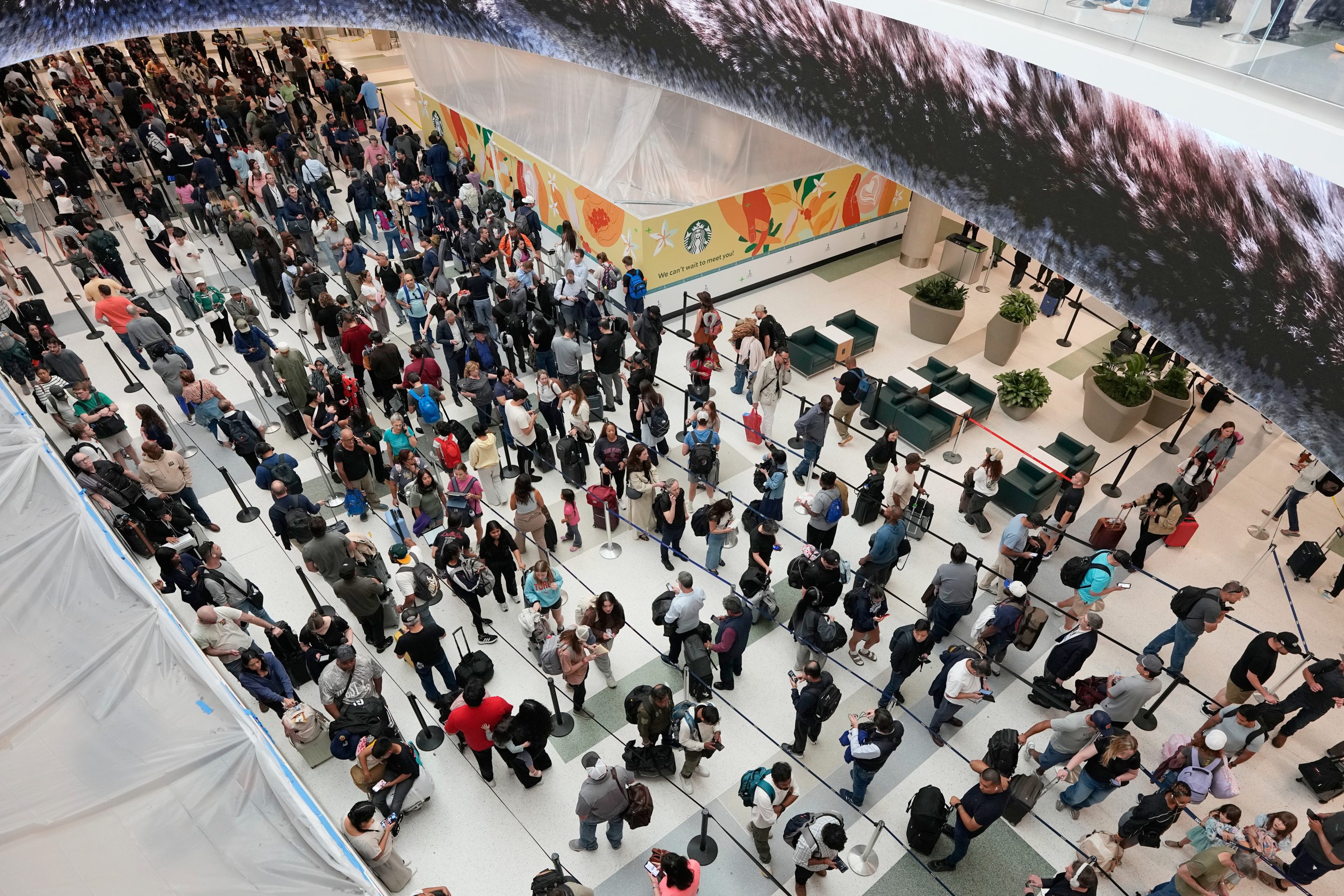 Travelers wait in long security checkpoint lines at George Bush Intercontinental Airport Friday, March 27, 2026, in Houston