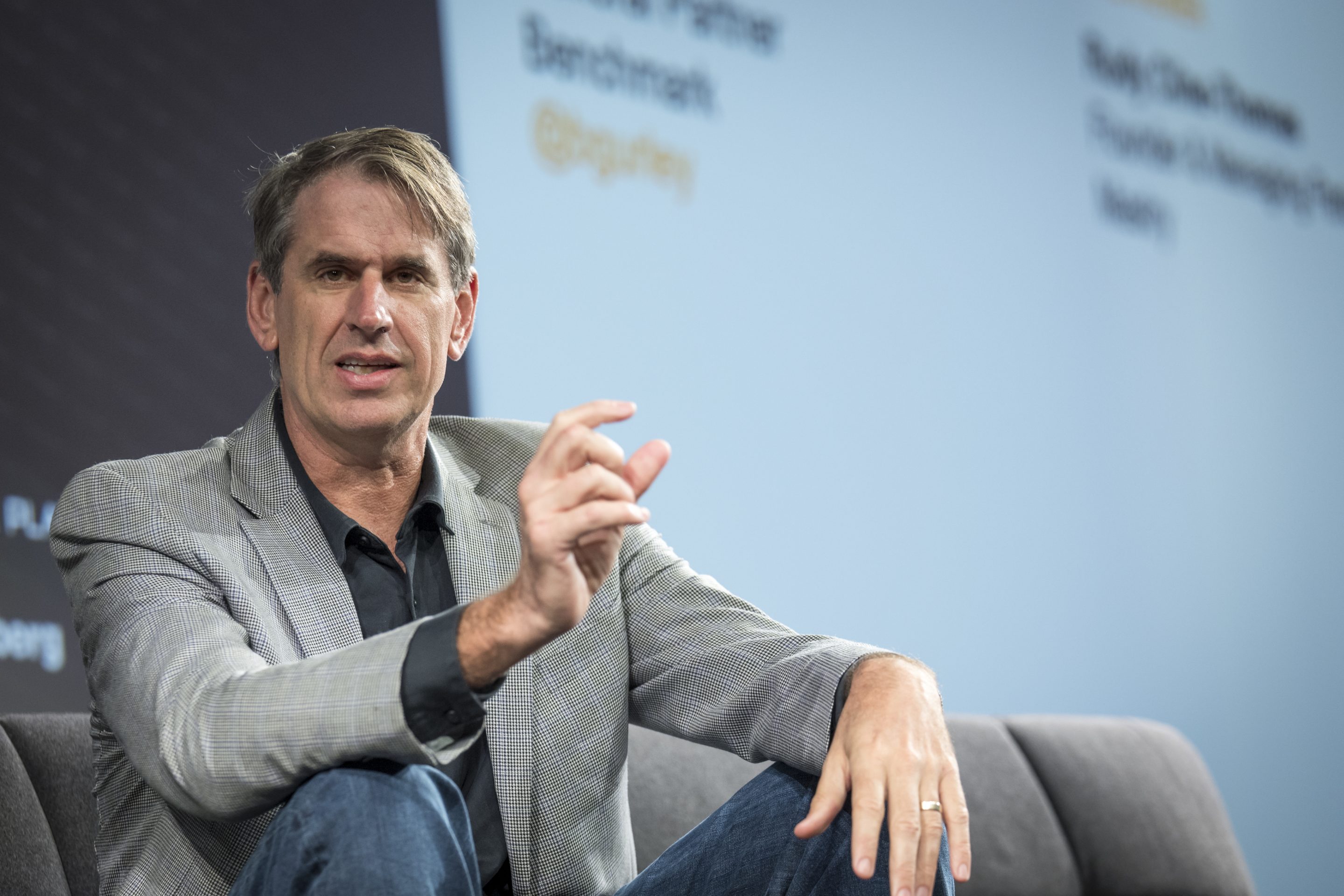 Bill Gurley sits onstage with his arms resting on his knees.