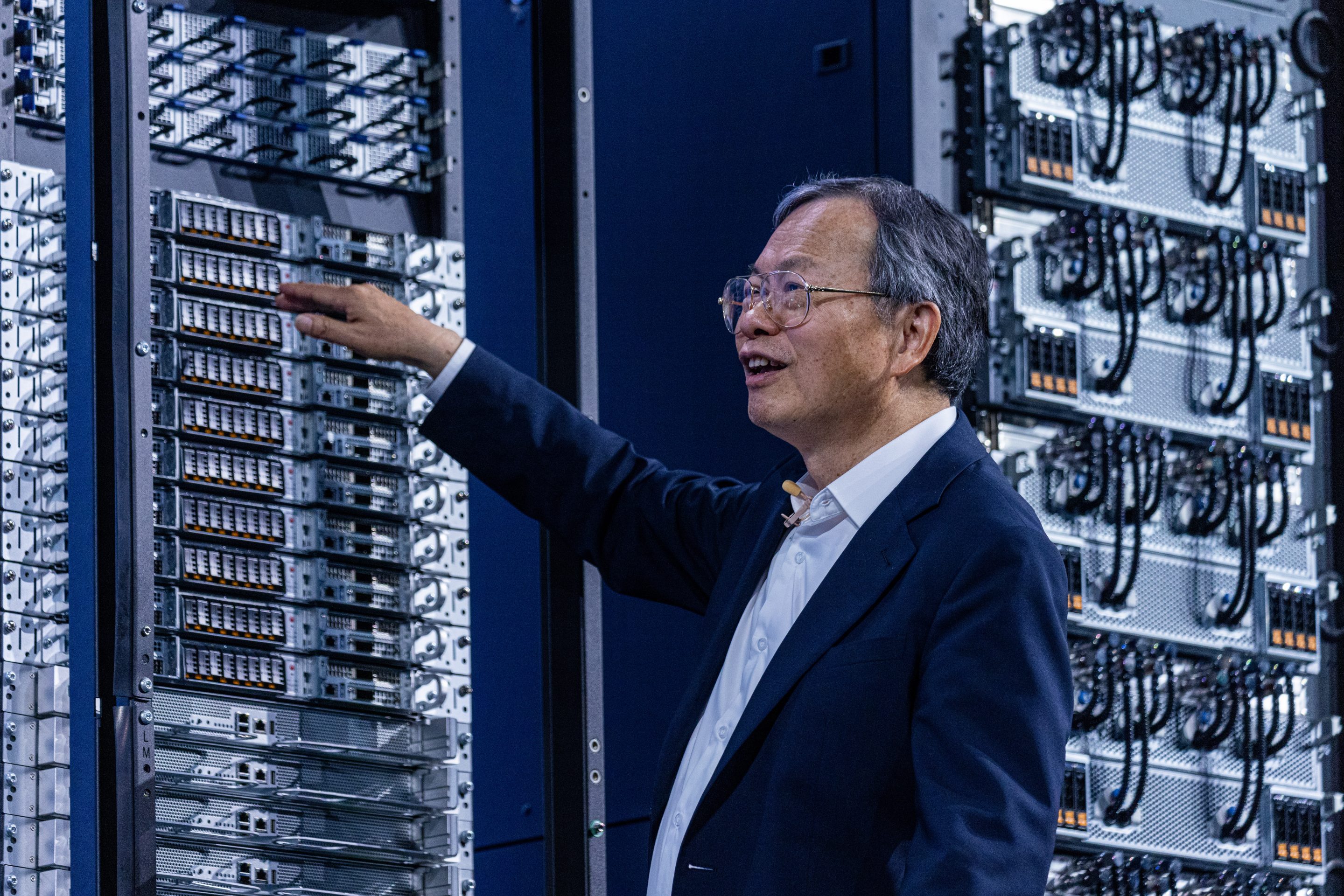 Man in a suit touches servers in a rack.