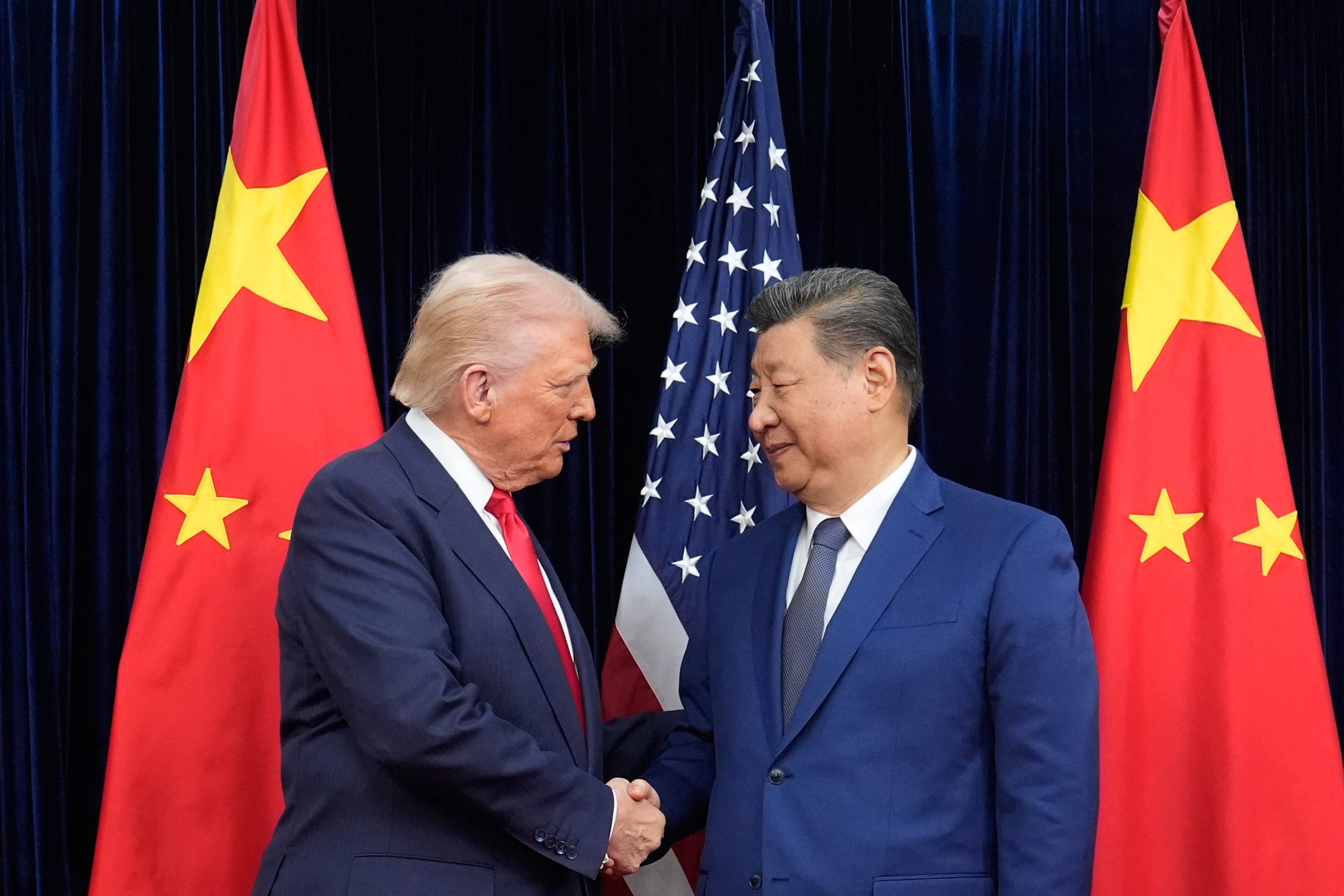 President Donald Trump, left, and Chinese President Xi Jinping, right, shake hands before their meeting at Gimhae International Airport in Busan, South Korea, Oct. 30, 2025.
