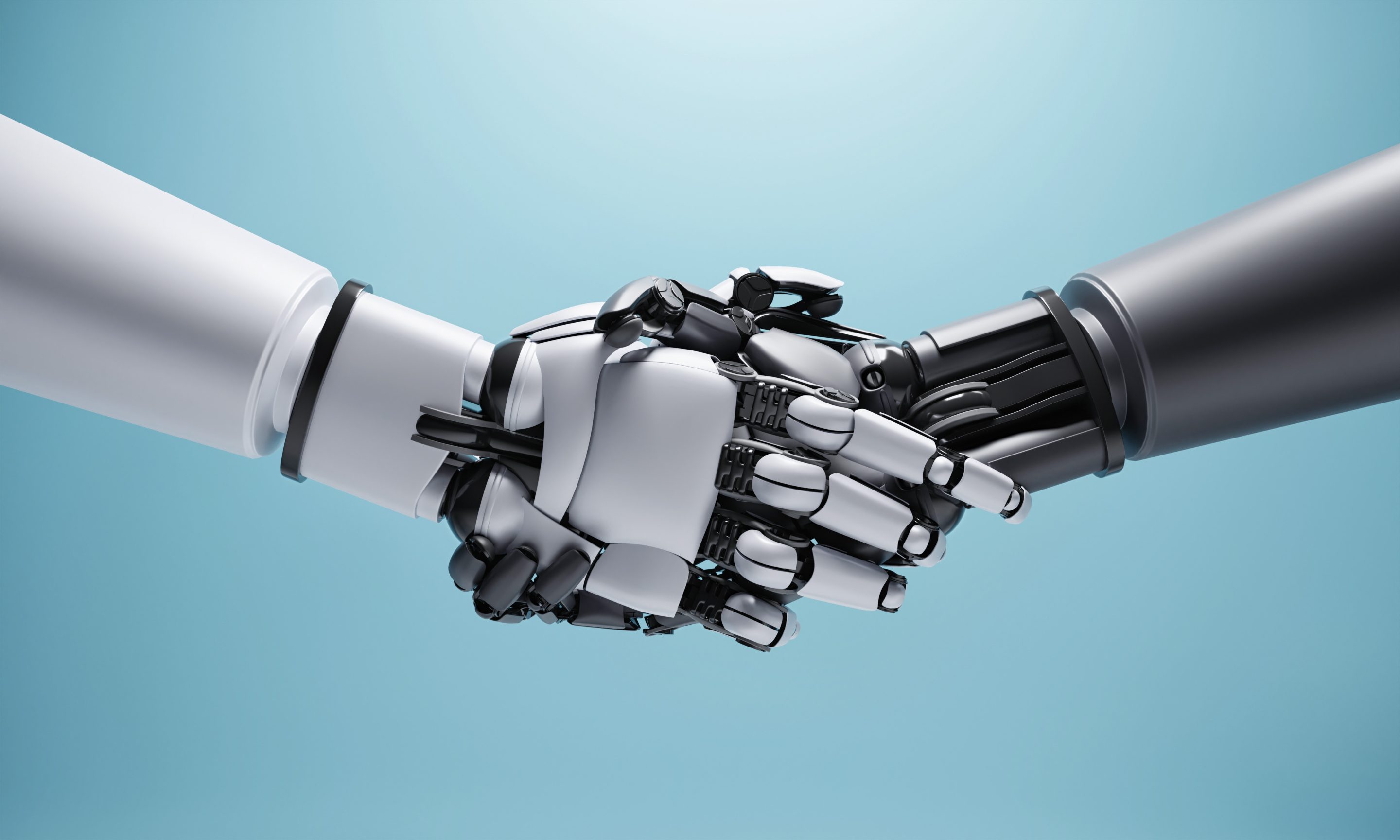 One humanoid robot handing shaking hands with another humanoid robotic hand. One robot on the left is lighter metal colored than the one on the right.