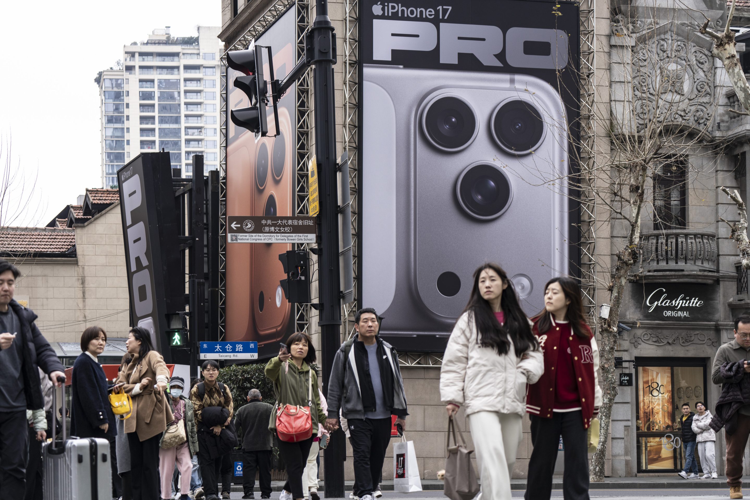 Shoppers pass an advertisement for the iPhone 17 Pro in the Xintiandi area in Shanghai, China, on Thursday, Feb. 19, 2026.