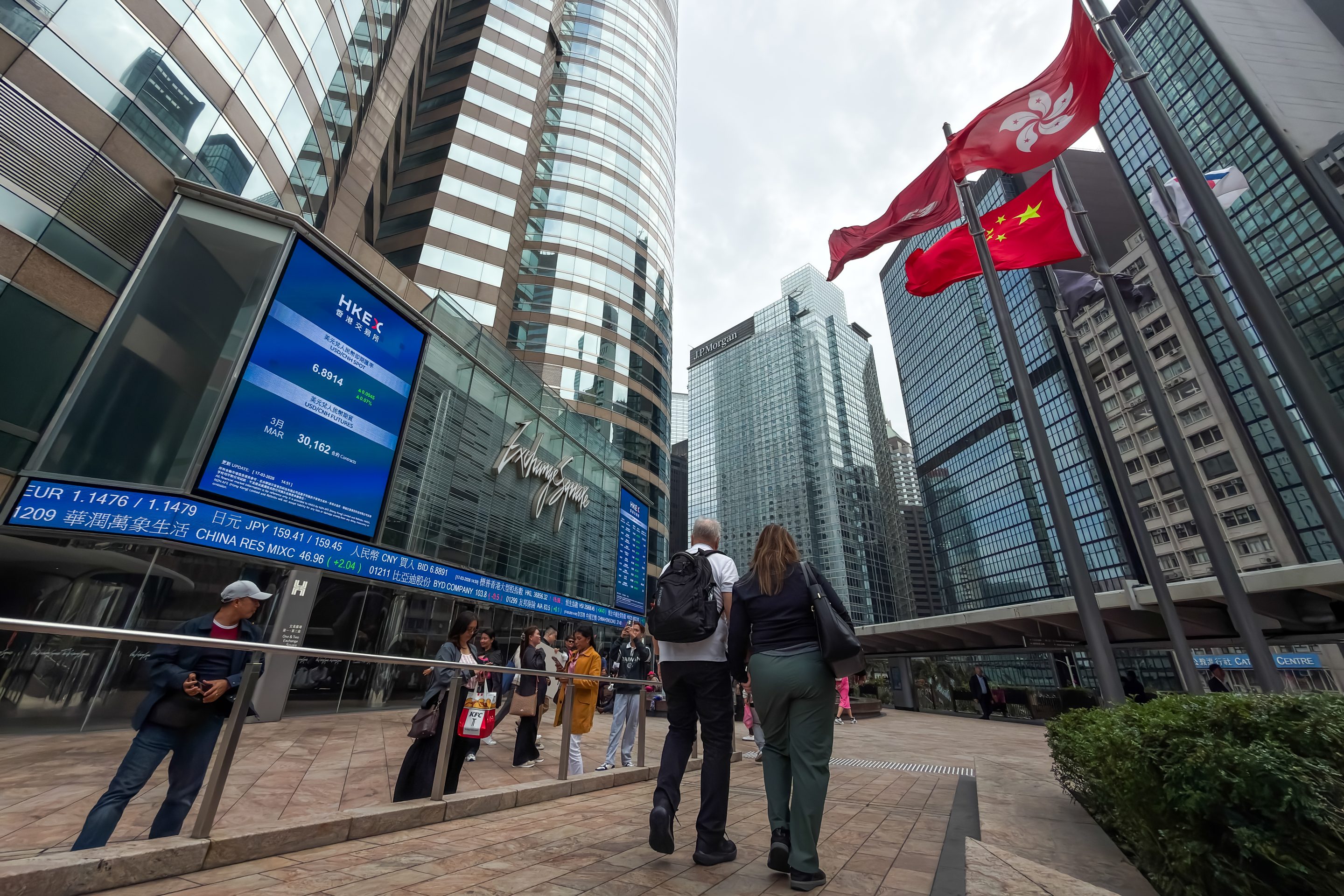 Pedestrians walk near the Exchange Square complex, home to Hong Kong Exchanges and Clearing (HKEX), on March 17, 2026 in Hong Kong, China.
