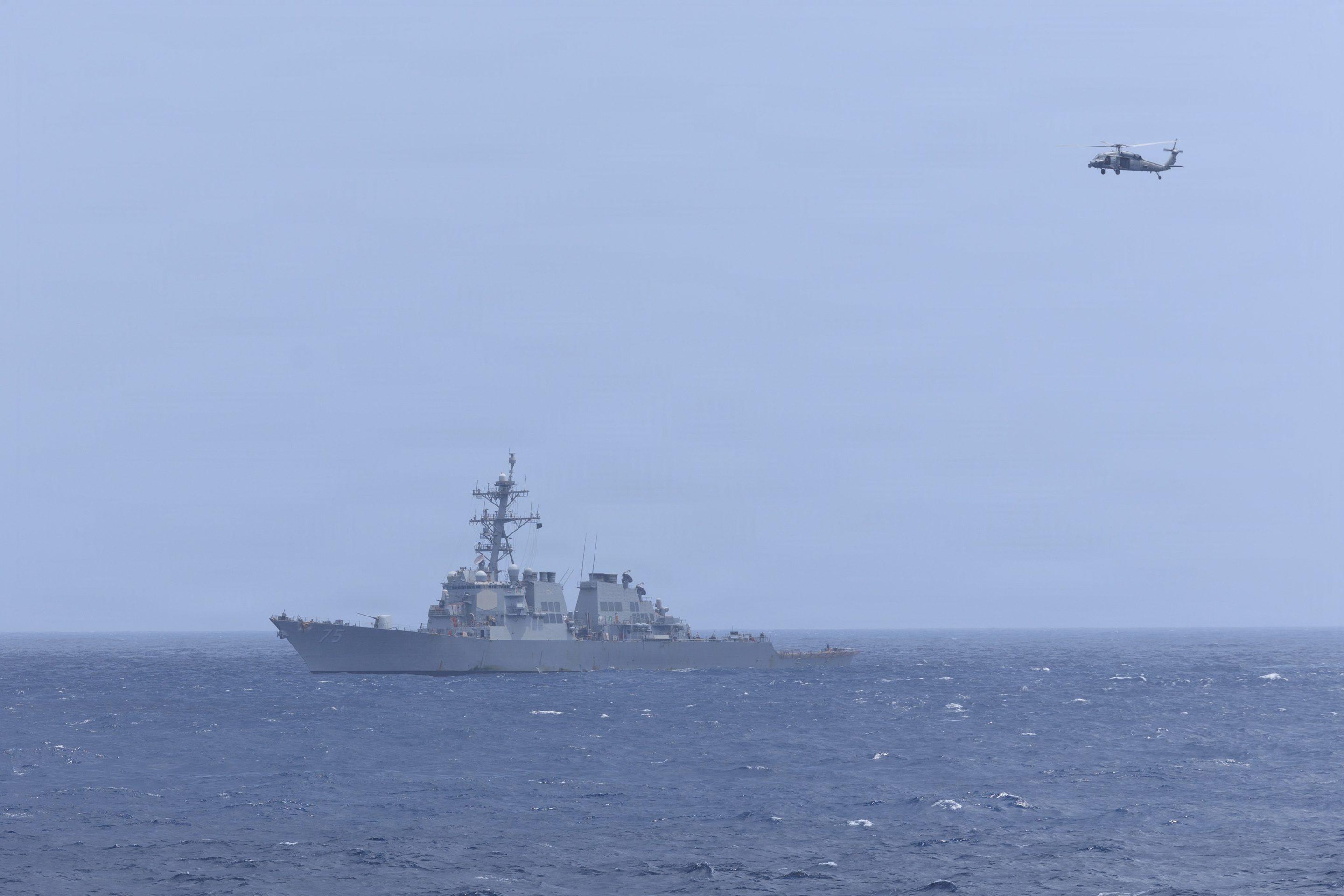 An MH-60S Sea Hawk, attached to Helicopter Sea Combat Squadron (HSC) 5, flies over Arleigh Burke-class guided-missile destroyer USS Donald Cook (DDG 75) while sailing alongside Nimitz-class aircraft carrier USS George H.W. Bush (CVN 77) while sailing in the Arabian Sea, June 17, 2026.
