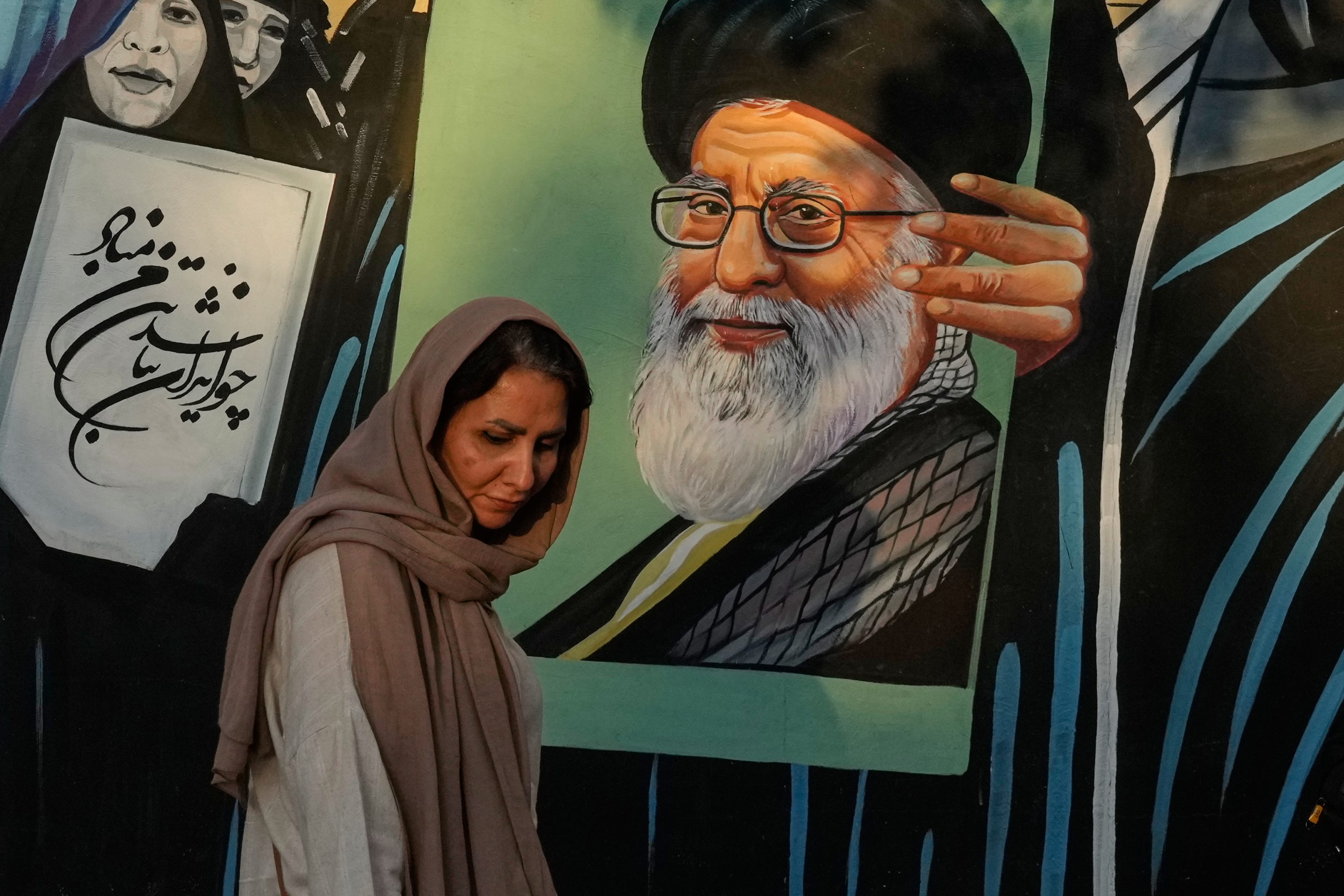 A woman walks past a mural depicting a portrait of the late Iranian Supreme Leader Ayatollah Ali Khamenei, who was killed in the U.S. and Israel strike on Feb. 28, in downtown Tehran, Iran, Saturday, July 18, 2026.