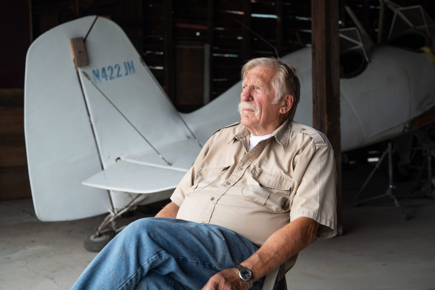 Alaskan pilot Ken Jouppi sits in an aircraft hanger in front of a plane.
